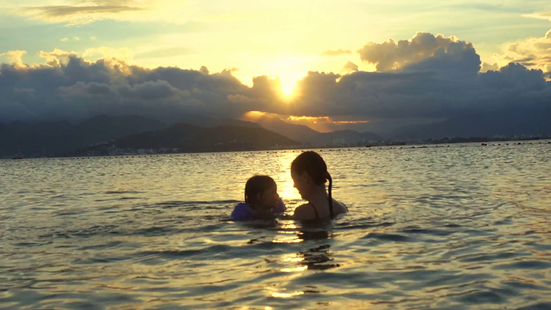 Silhouette of mother and child swimming in the sea at sunset. Family ...