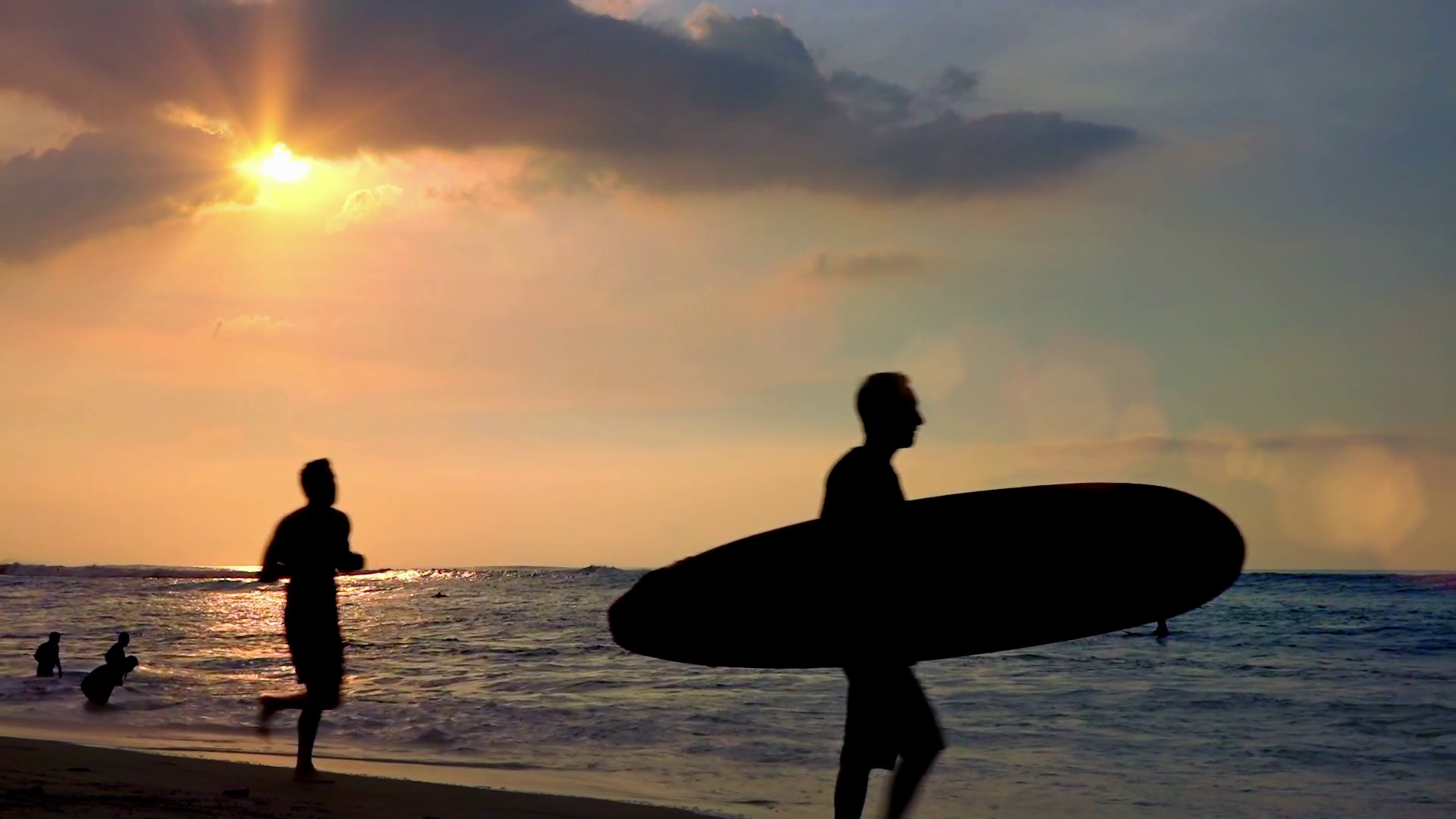 Silhouettes of surfer carrying surfboard and man running along ...