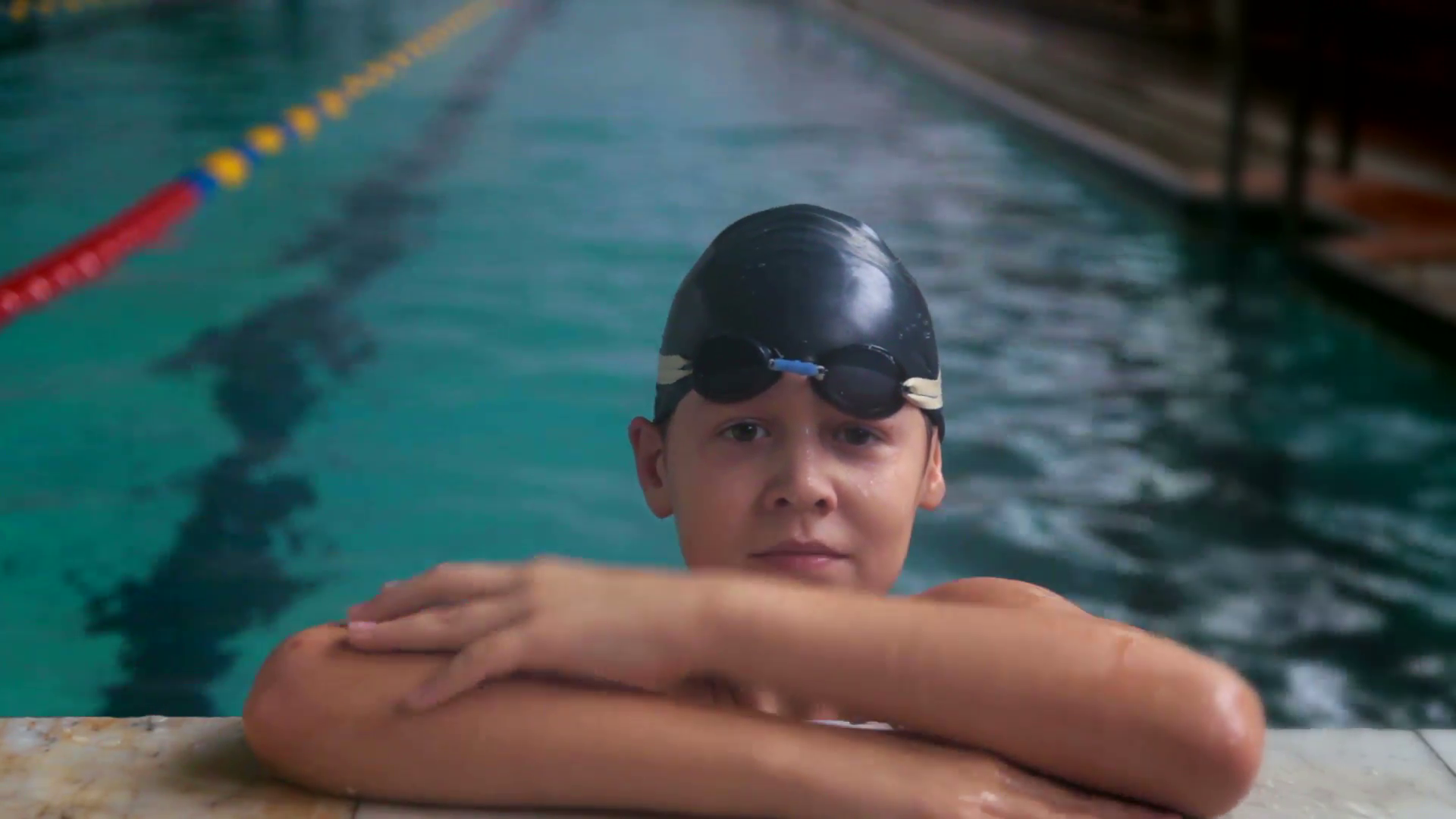 Portrait of teenage boy swimmer wearing goggles and cap relaxes at ...