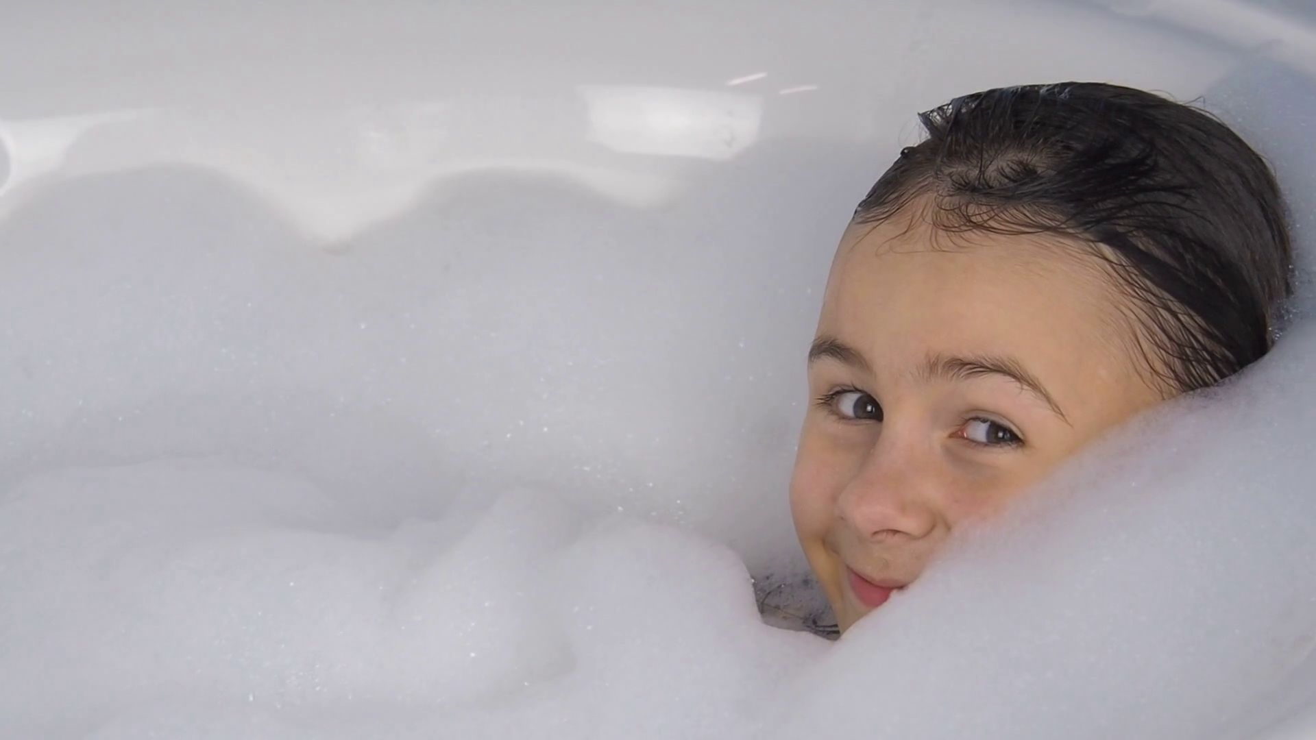 The child is taking a bath. Little girl is playing in the foam in ...