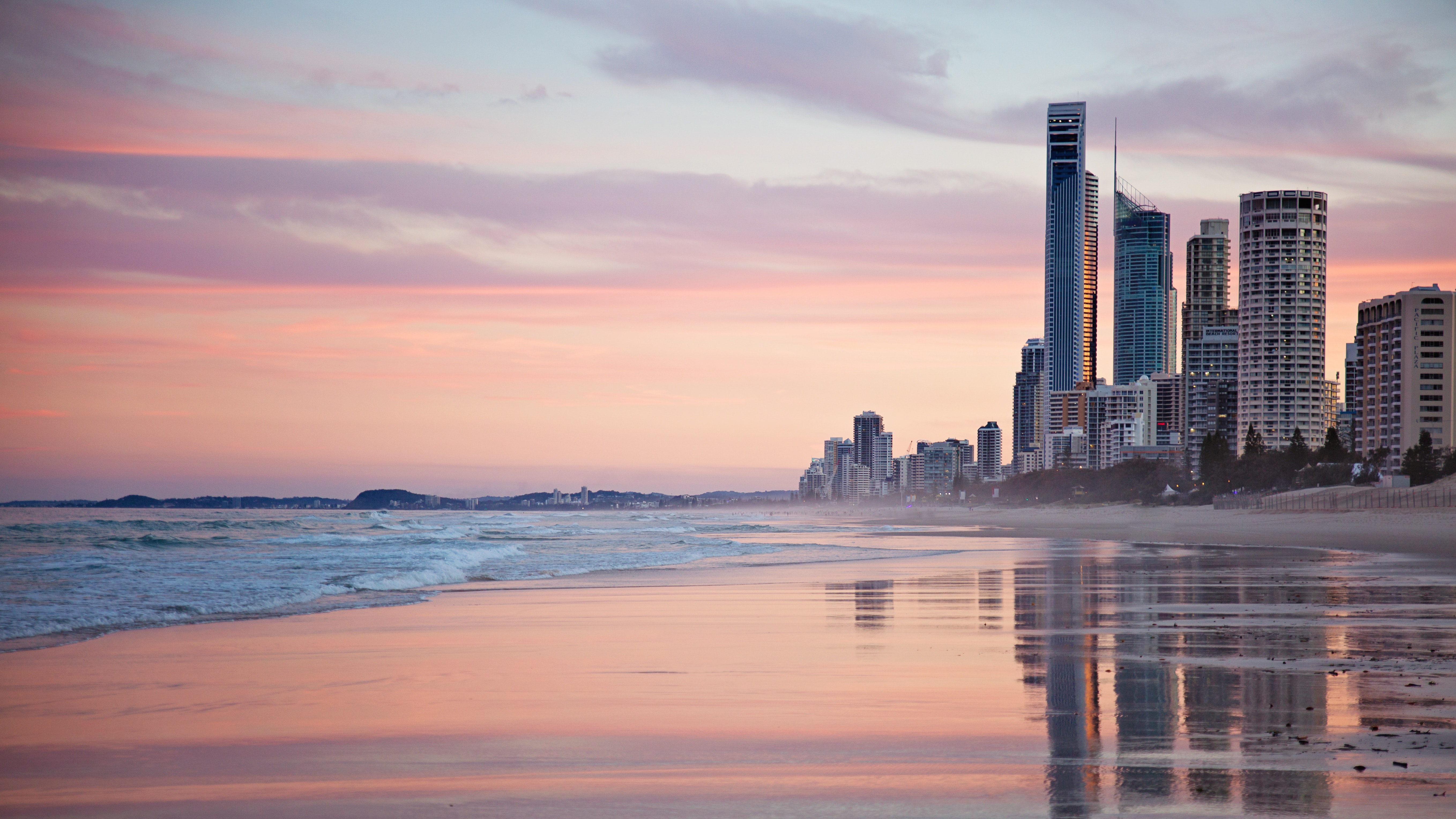 Tall city buildings near beach shore during sunset photo