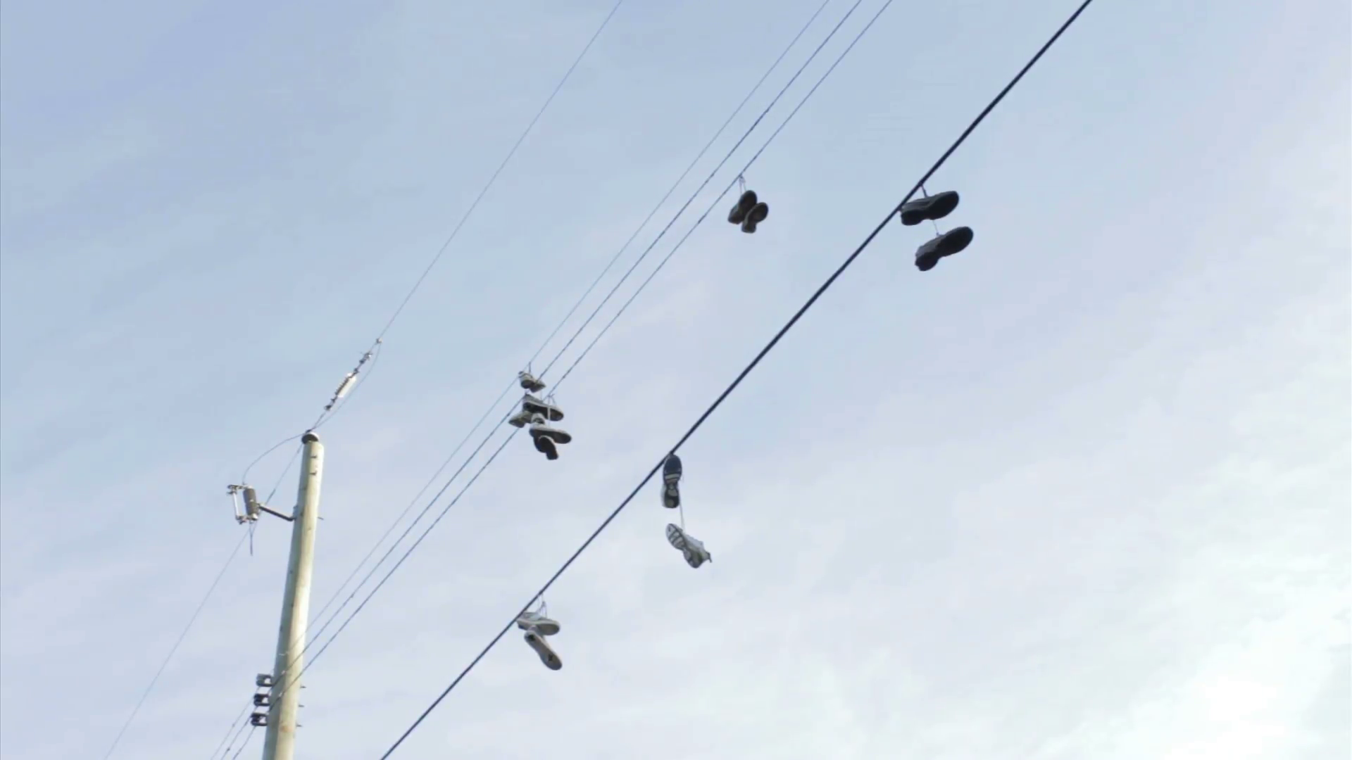 A whole bunch of running shoes hanging on some telephone wires in ...
