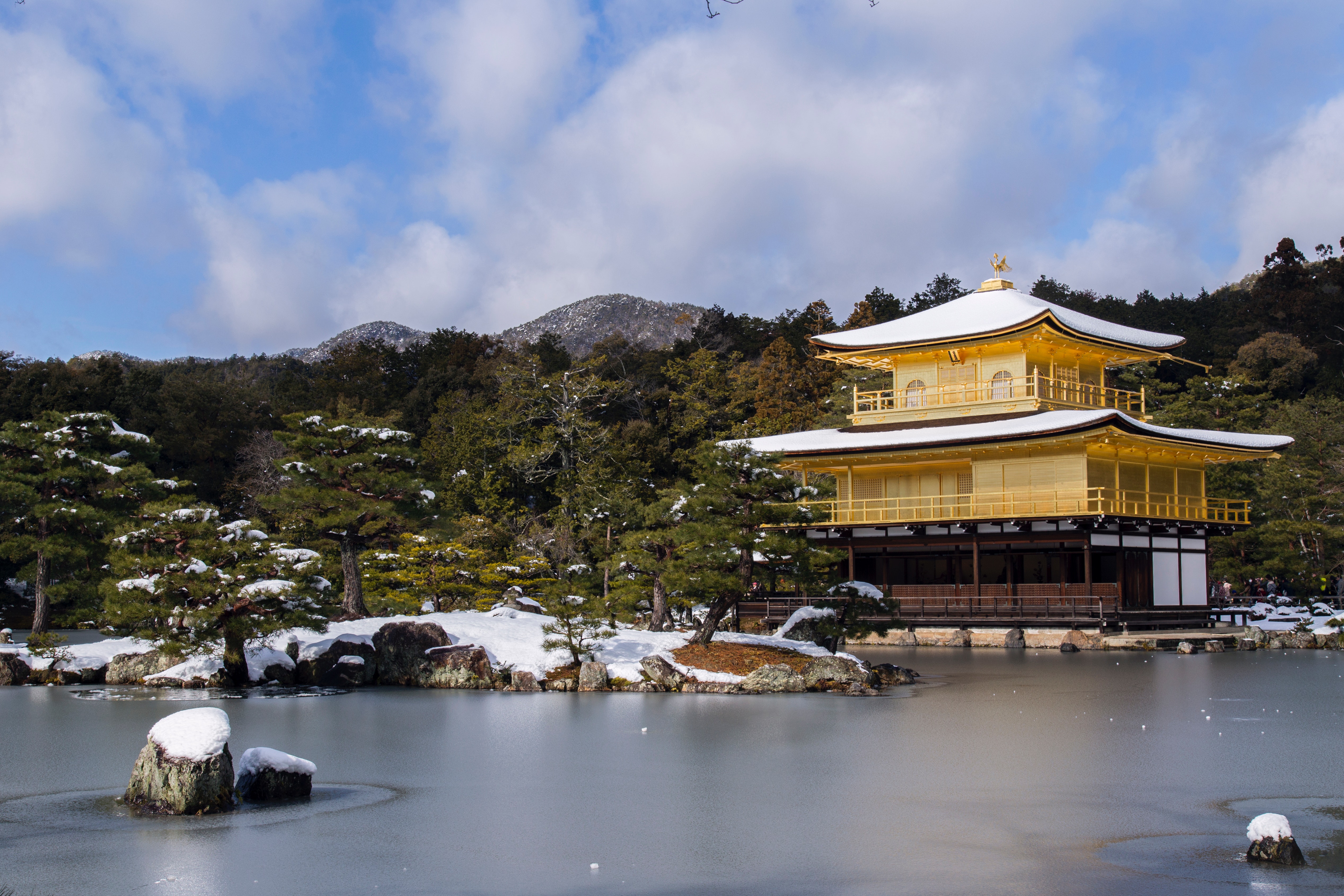 Temple near body of water surrounded by trees with mountain background photo