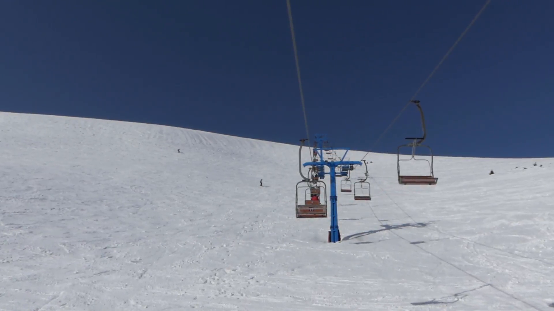 Empty seats of the chair lift go down from the top of mountain. The ...