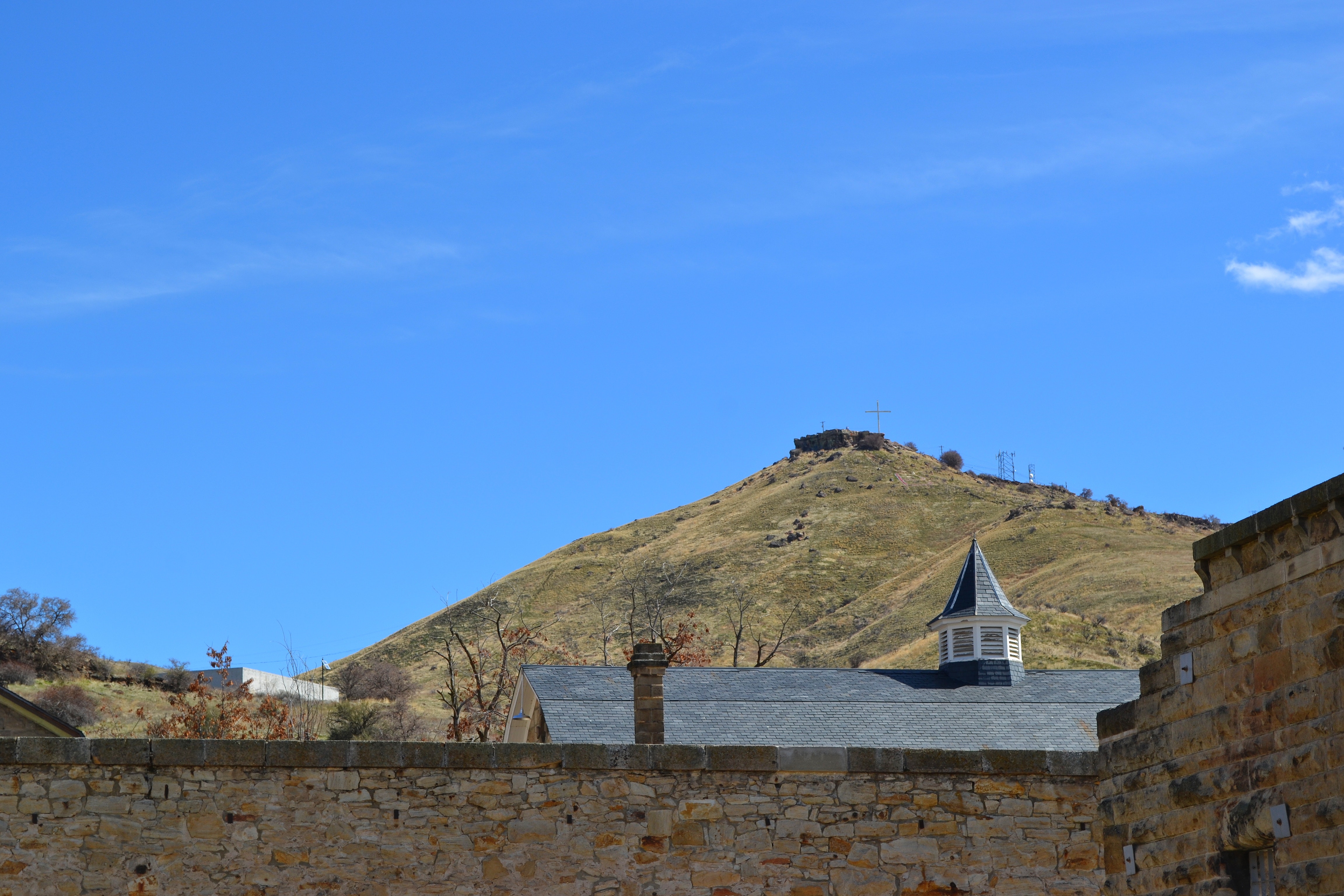 The wall of the fortress with a view of the hill with a cross photo
