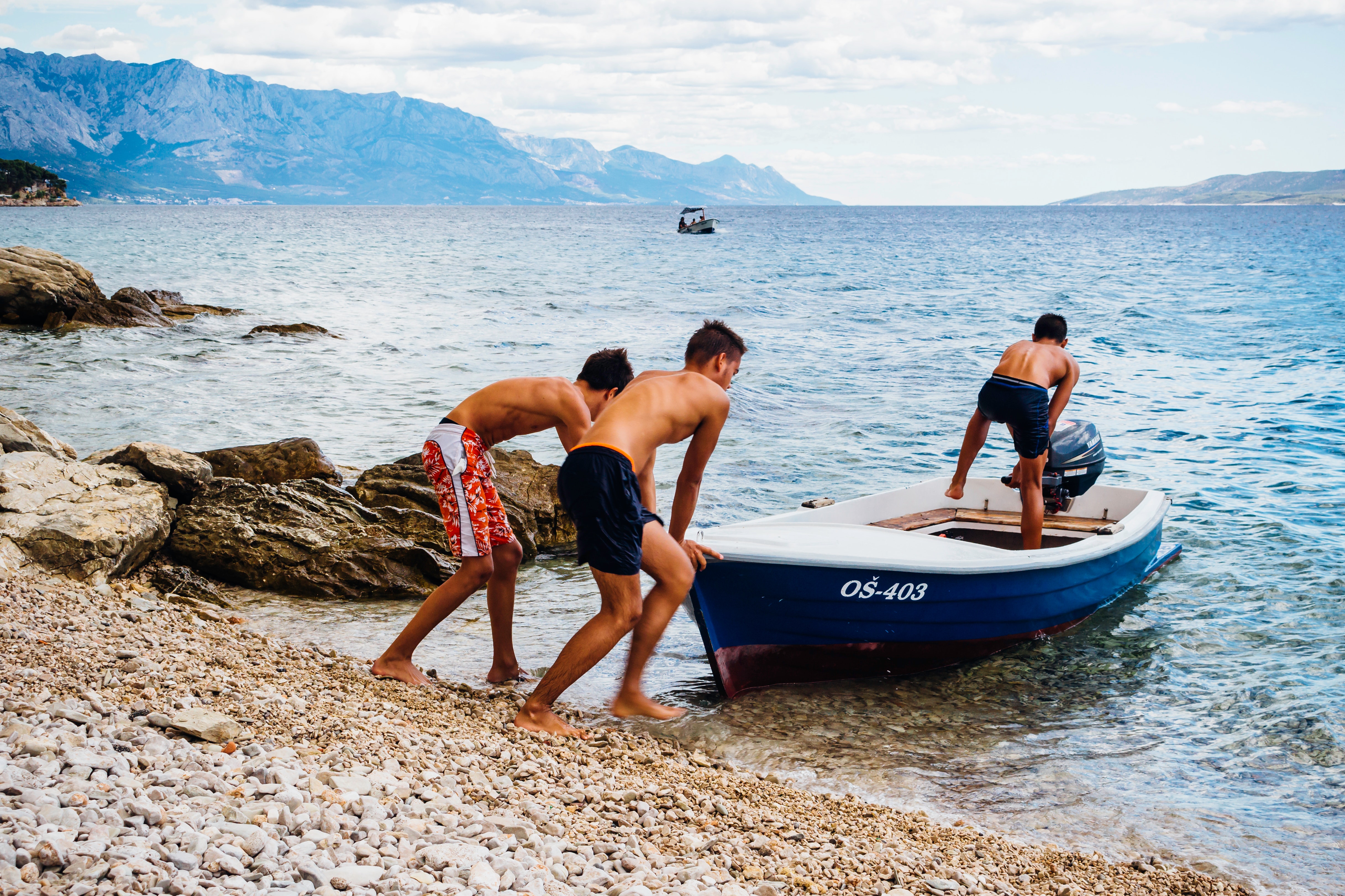 Three men pushing speed boat on seashore photo