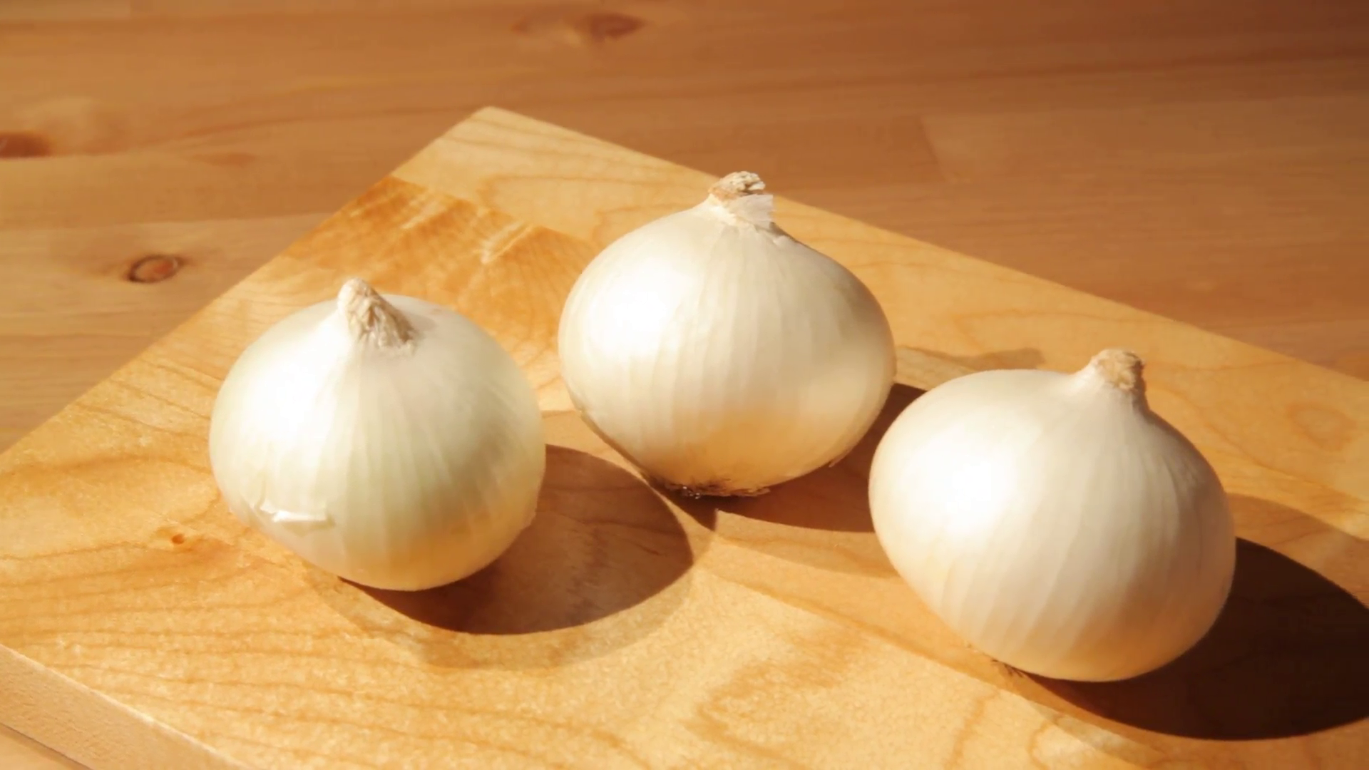 Three onions on a wooden board Stock Video Footage - VideoBlocks