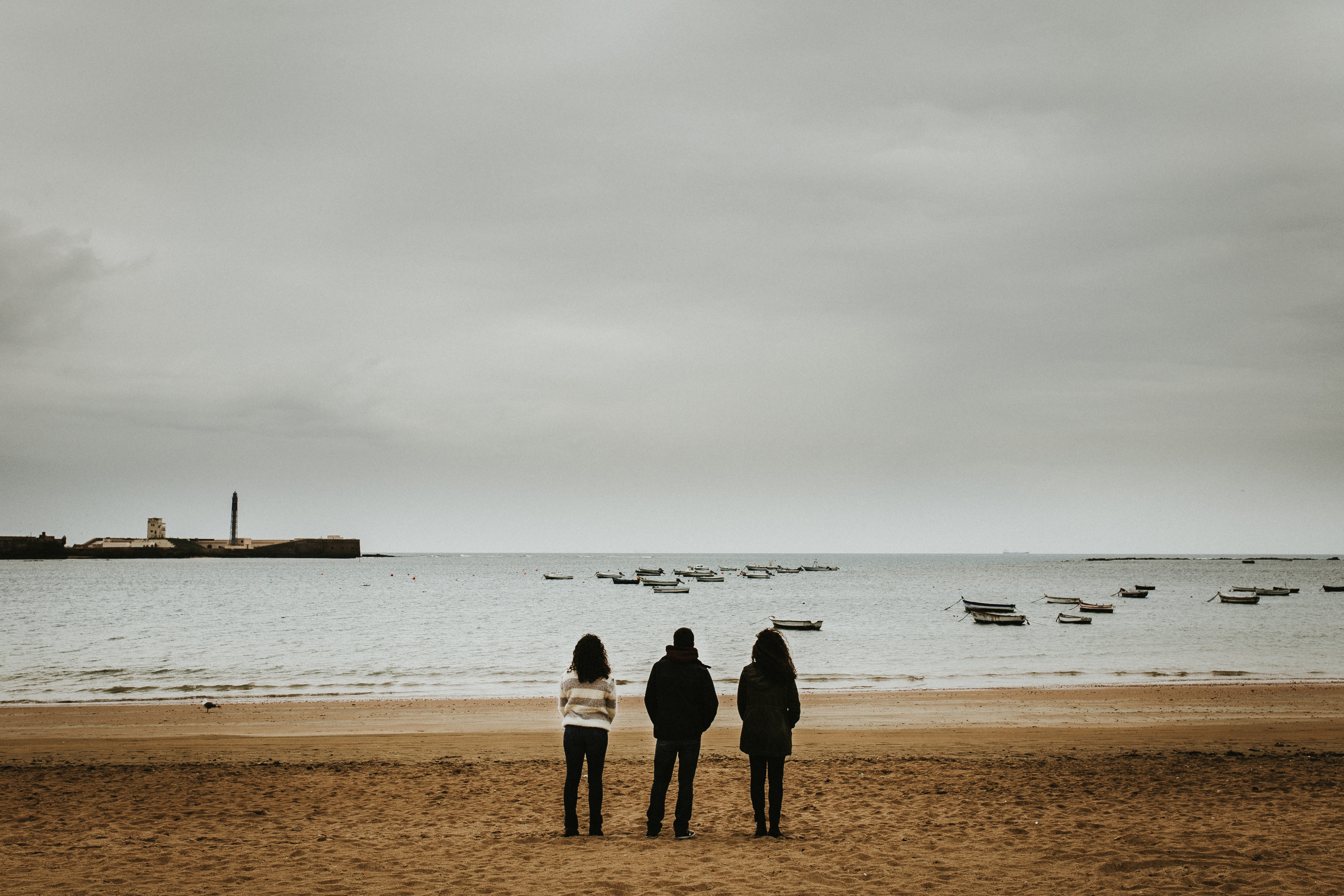 Three person standing near the seashore photo