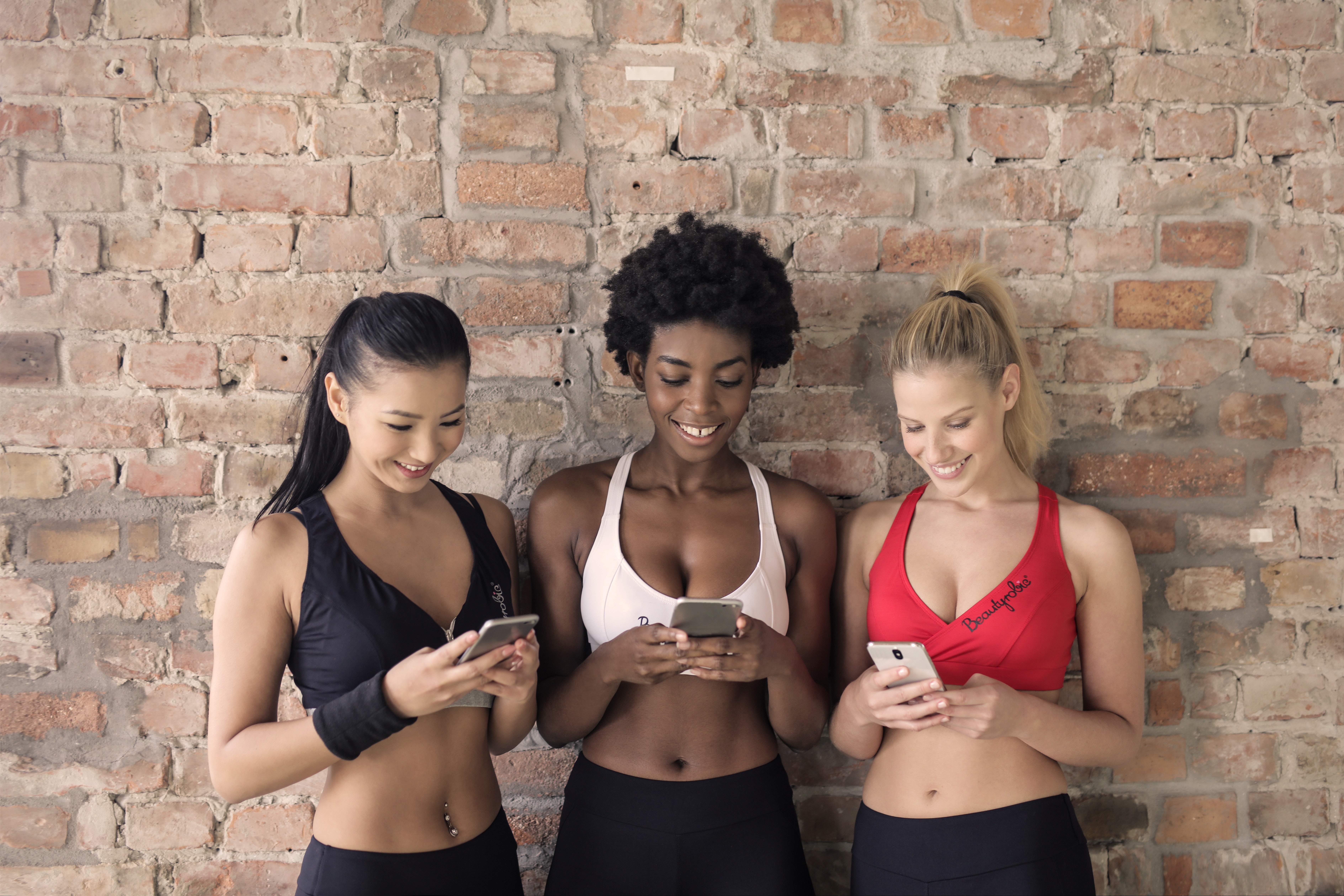 Three Woman in Assorted-color Sport Bras Holding and Watching Their Smartphones, Active, Smile, Mobile phone, People, HQ Photo
