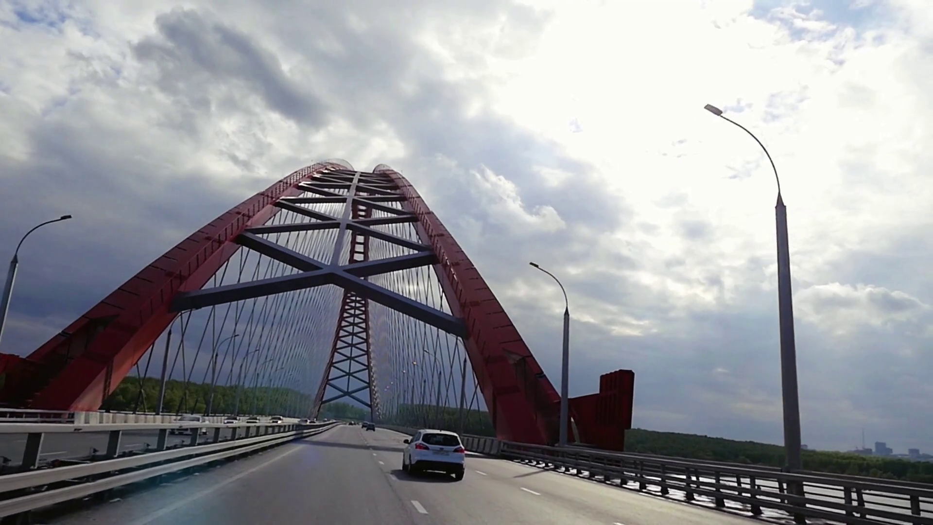 Road through the bridge with cloudy sky and moving cars in ...