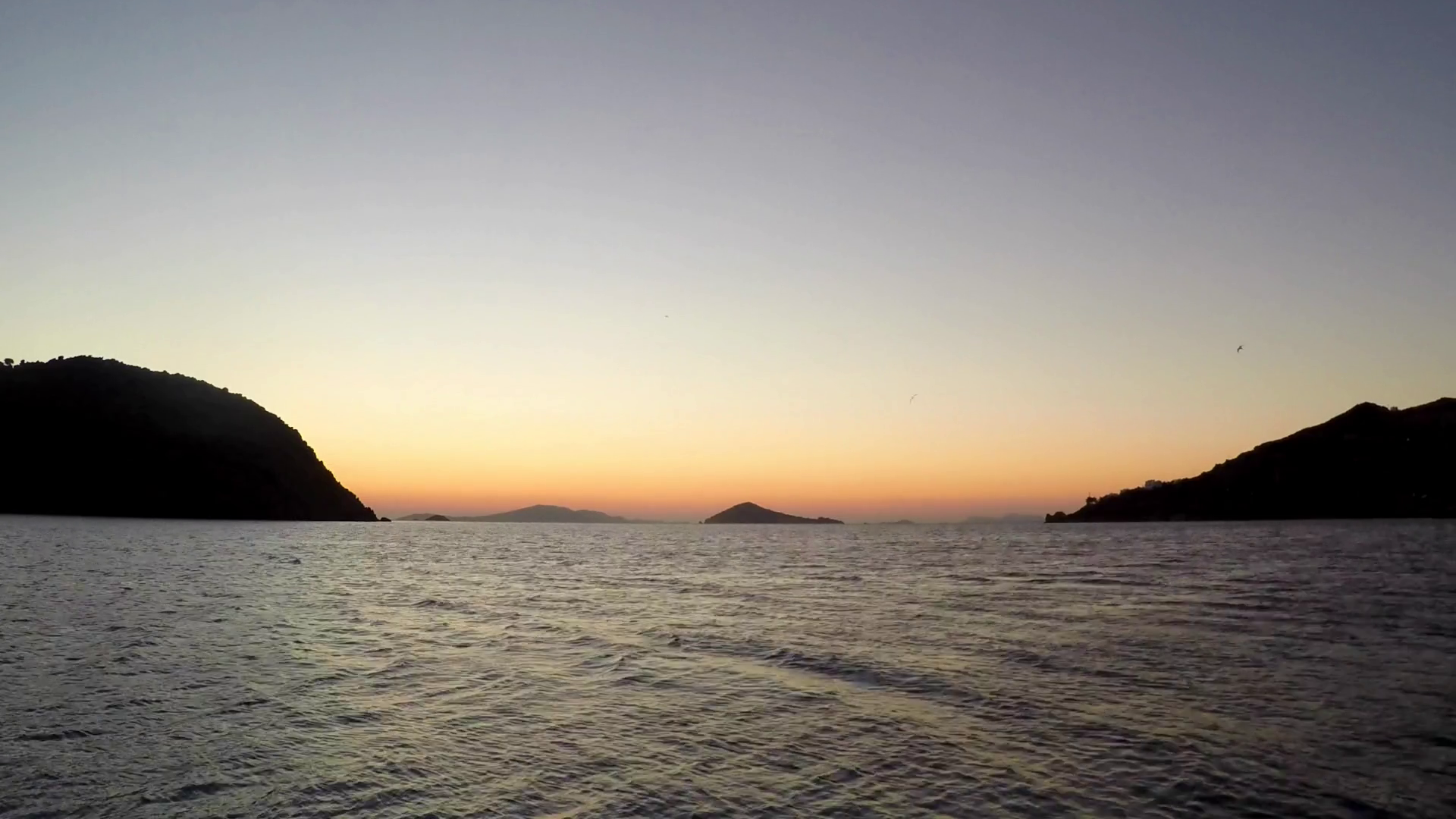 Timelapse boat sails towards the horizon as the sun rises over Greek ...