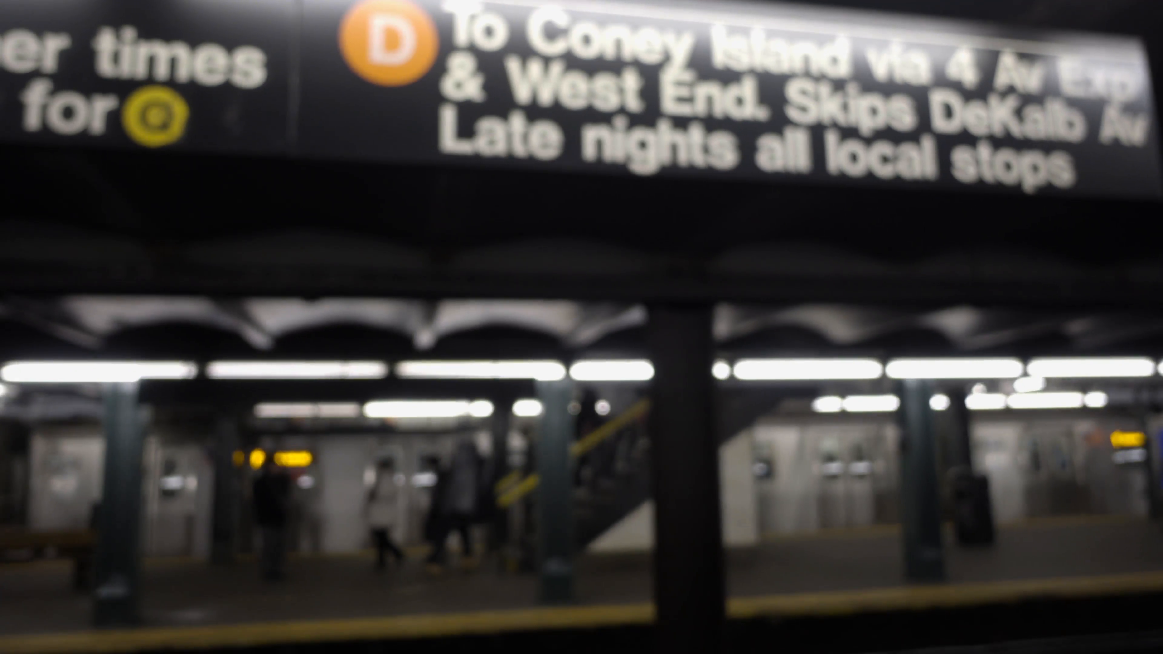 subway leaving station with D train sign to Coney Island on platform ...