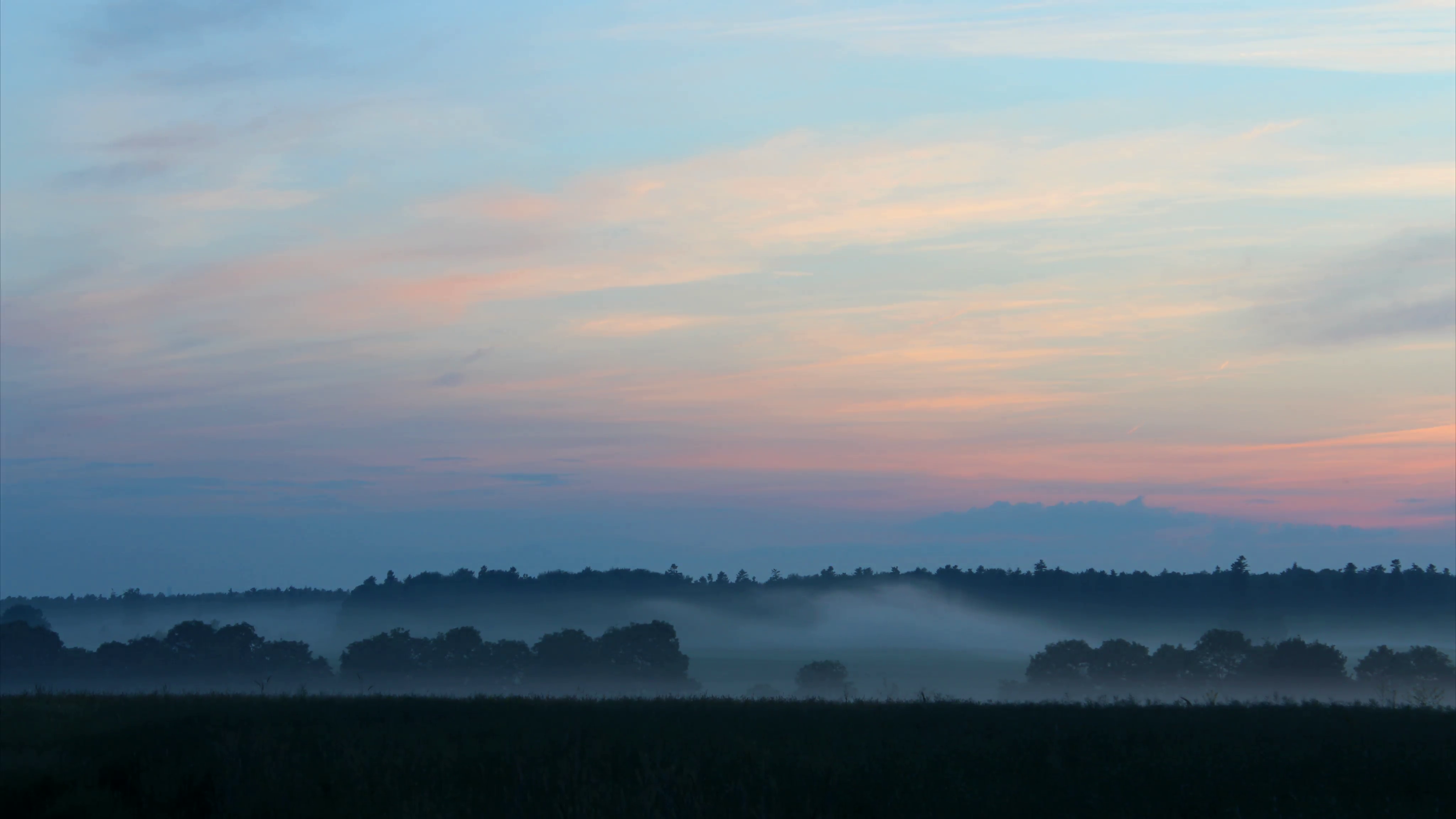 Fog dancing in a field against a colorful twilight sky. 4K timelapse ...