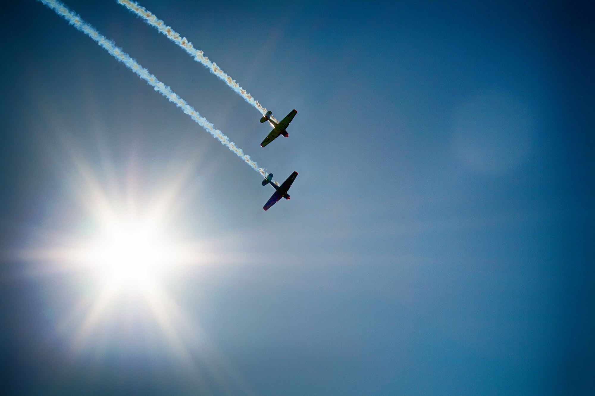Two airplane flying under blue sky emitting white smoke photo