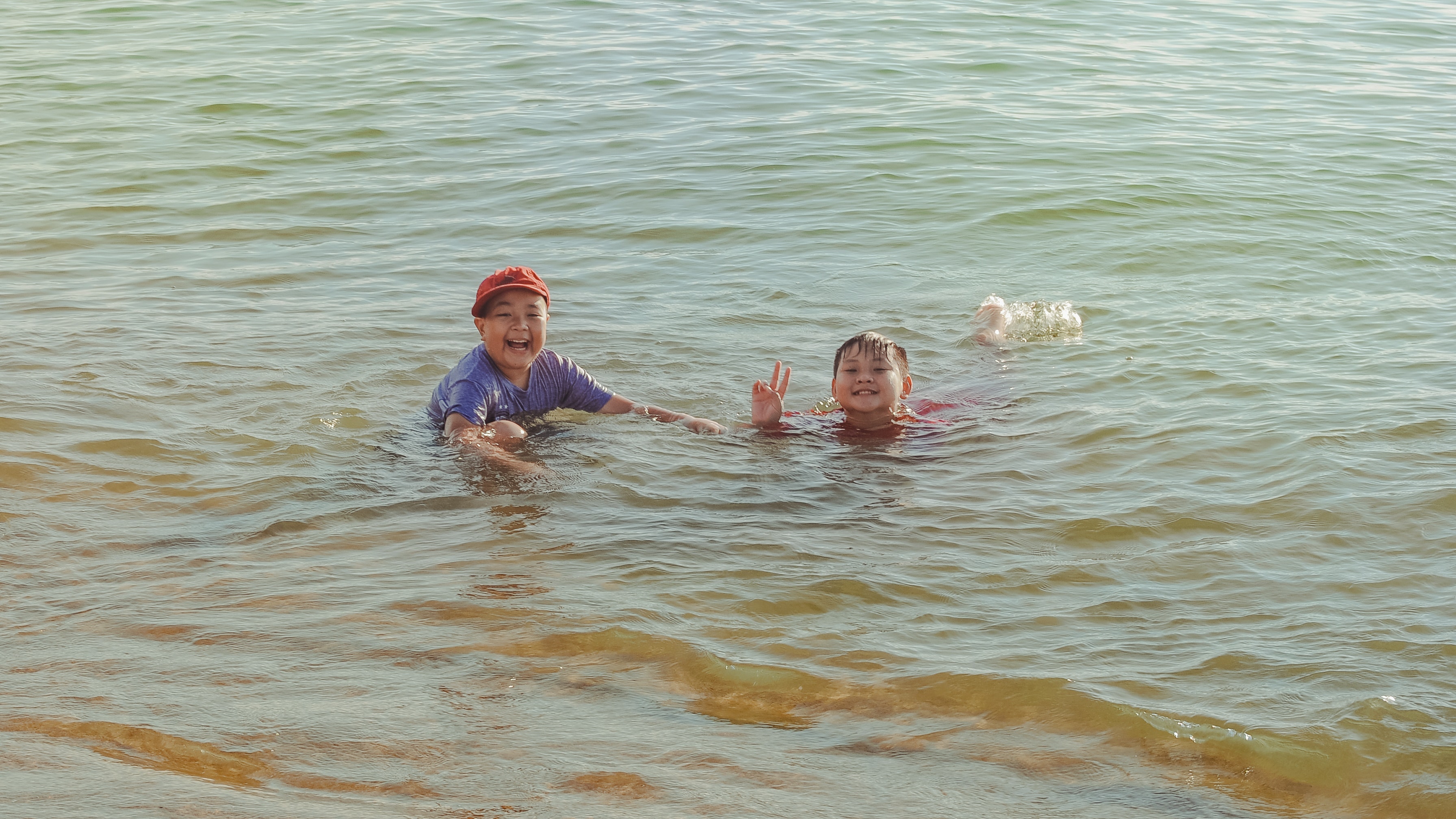 Two boy on brown body of water photo