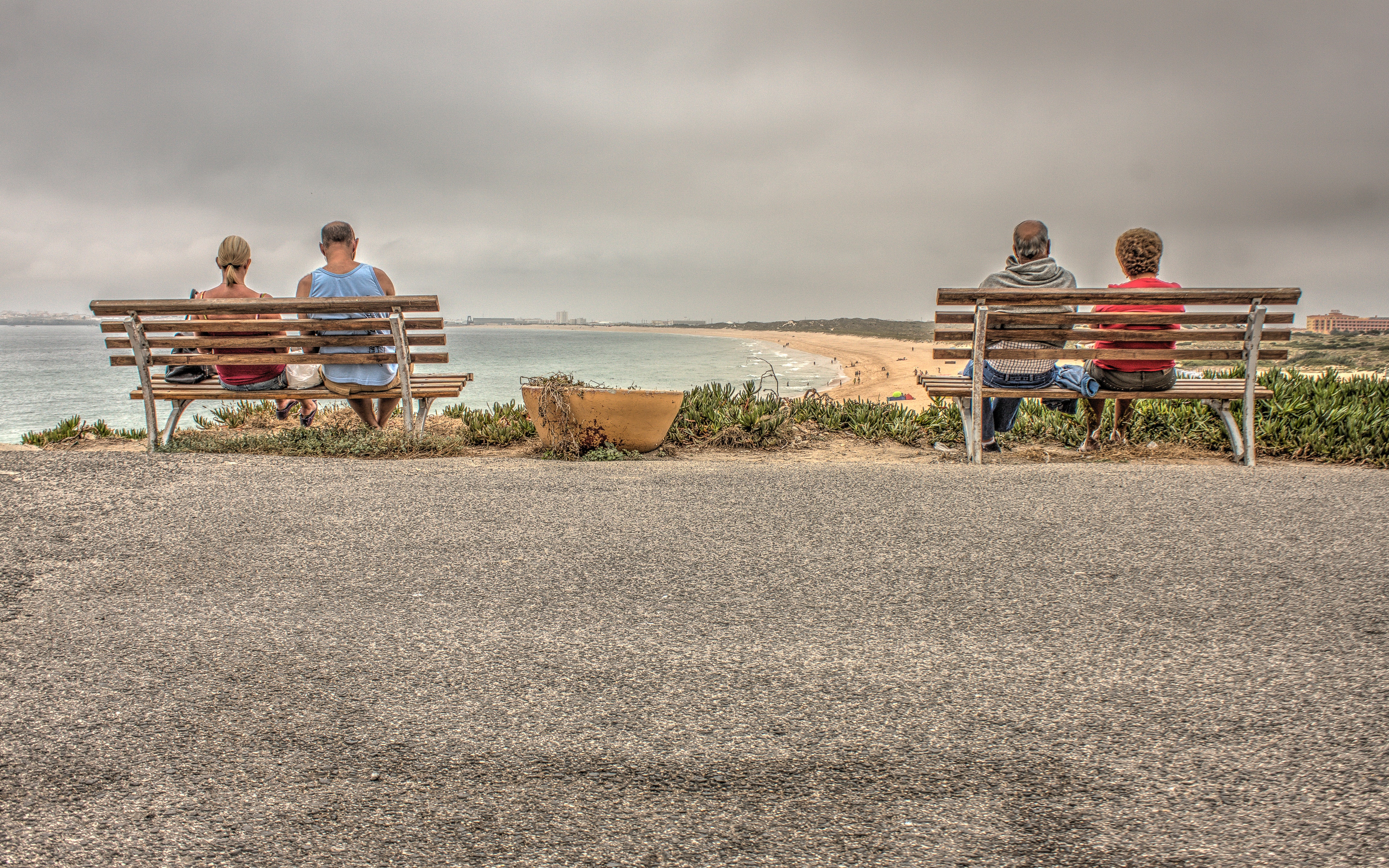 Two couple sitting on bench near beach photo
