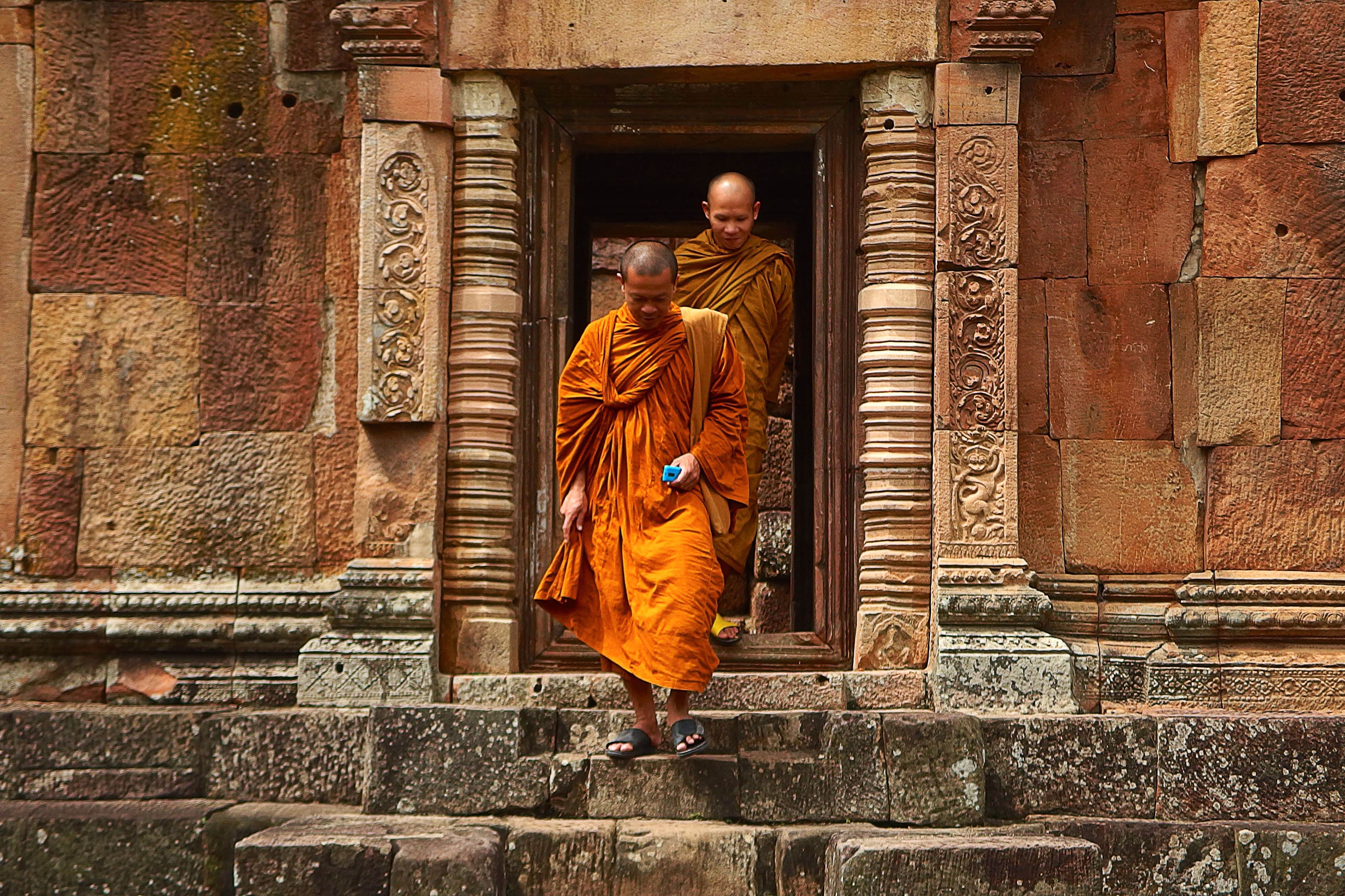 Two monk in orange robe walking down the concrete stairs photo