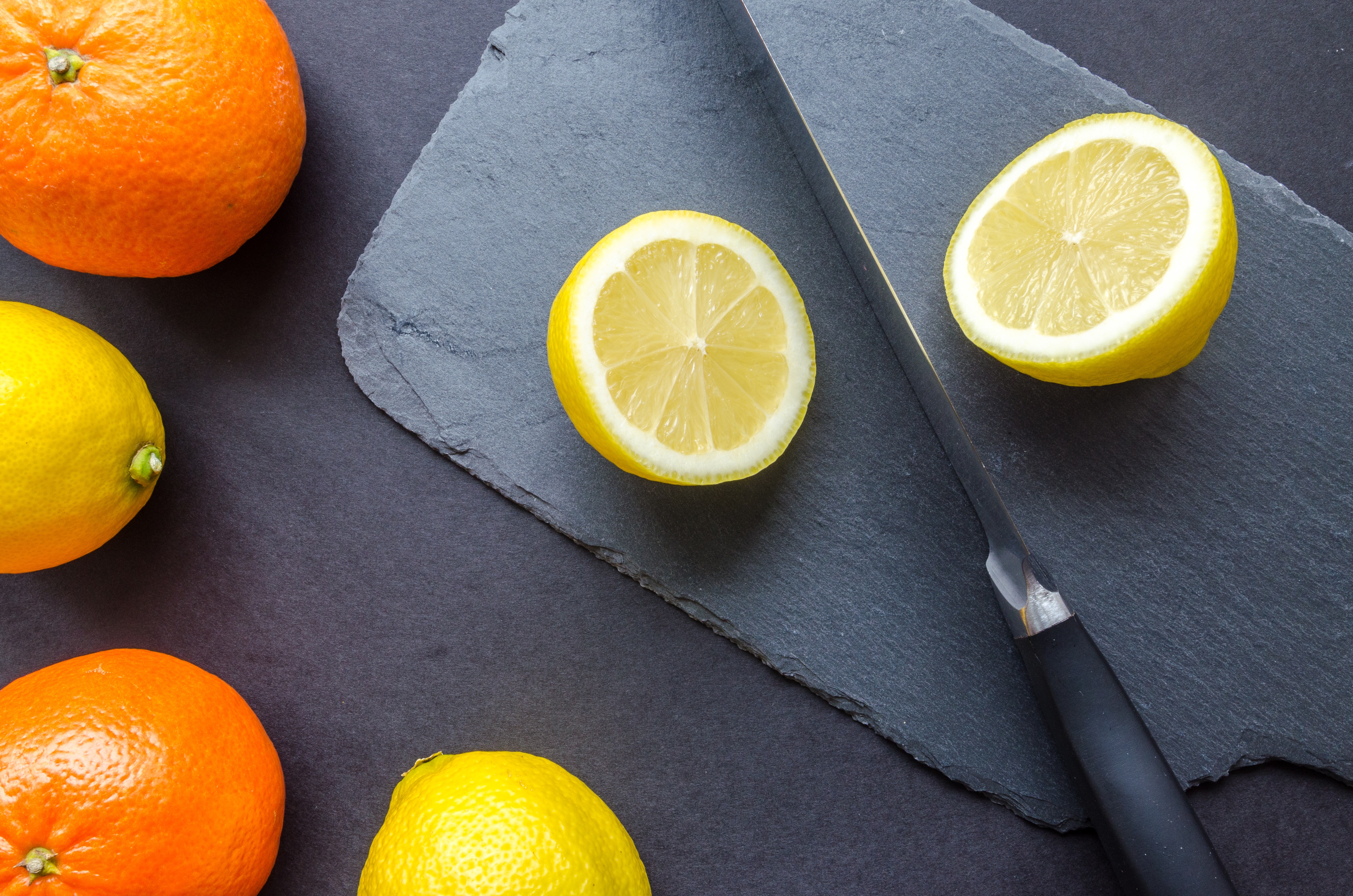 Two orange and three lemons on gray surface photo