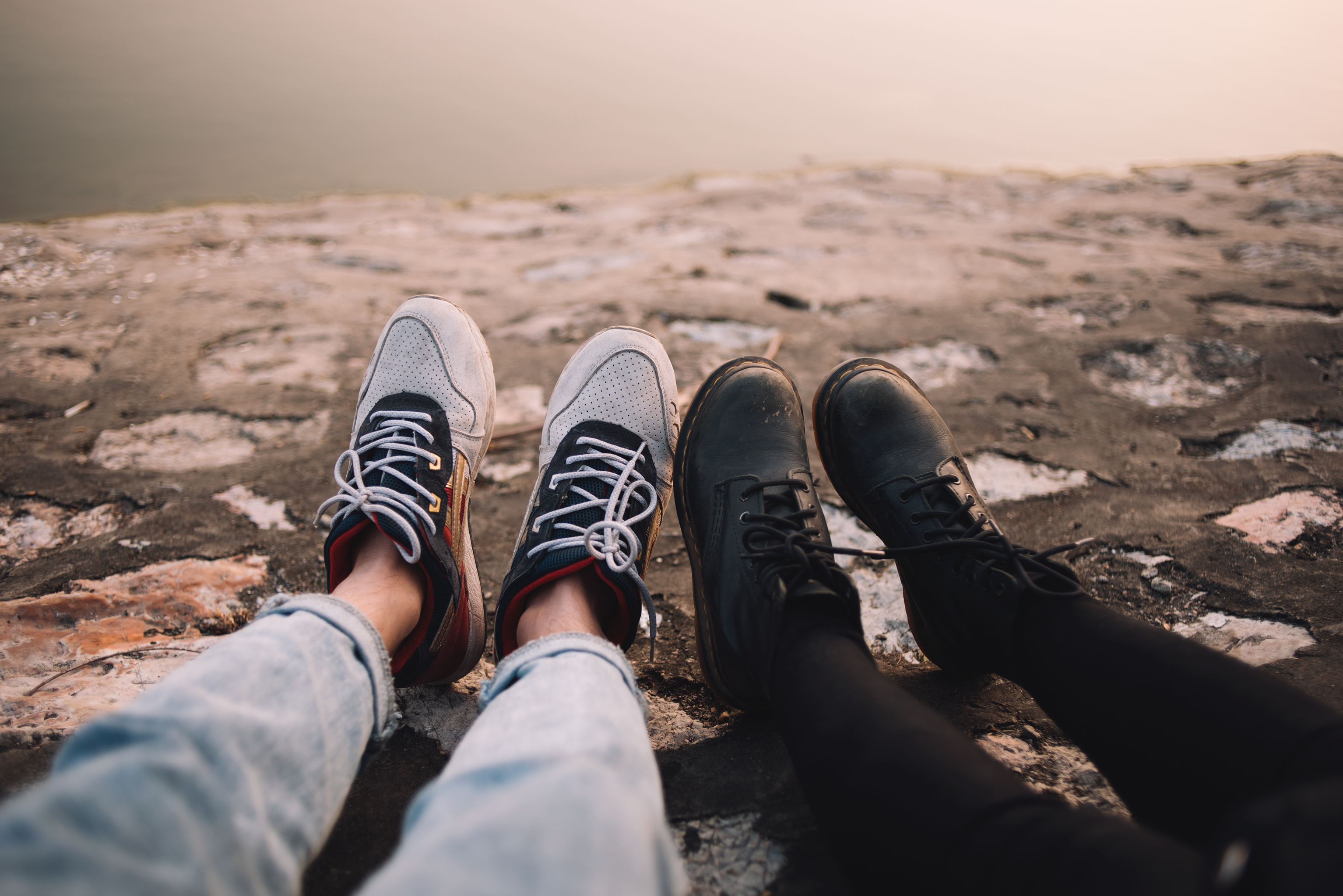 Two person wearing pants and shoes sits on ground at daytime photo