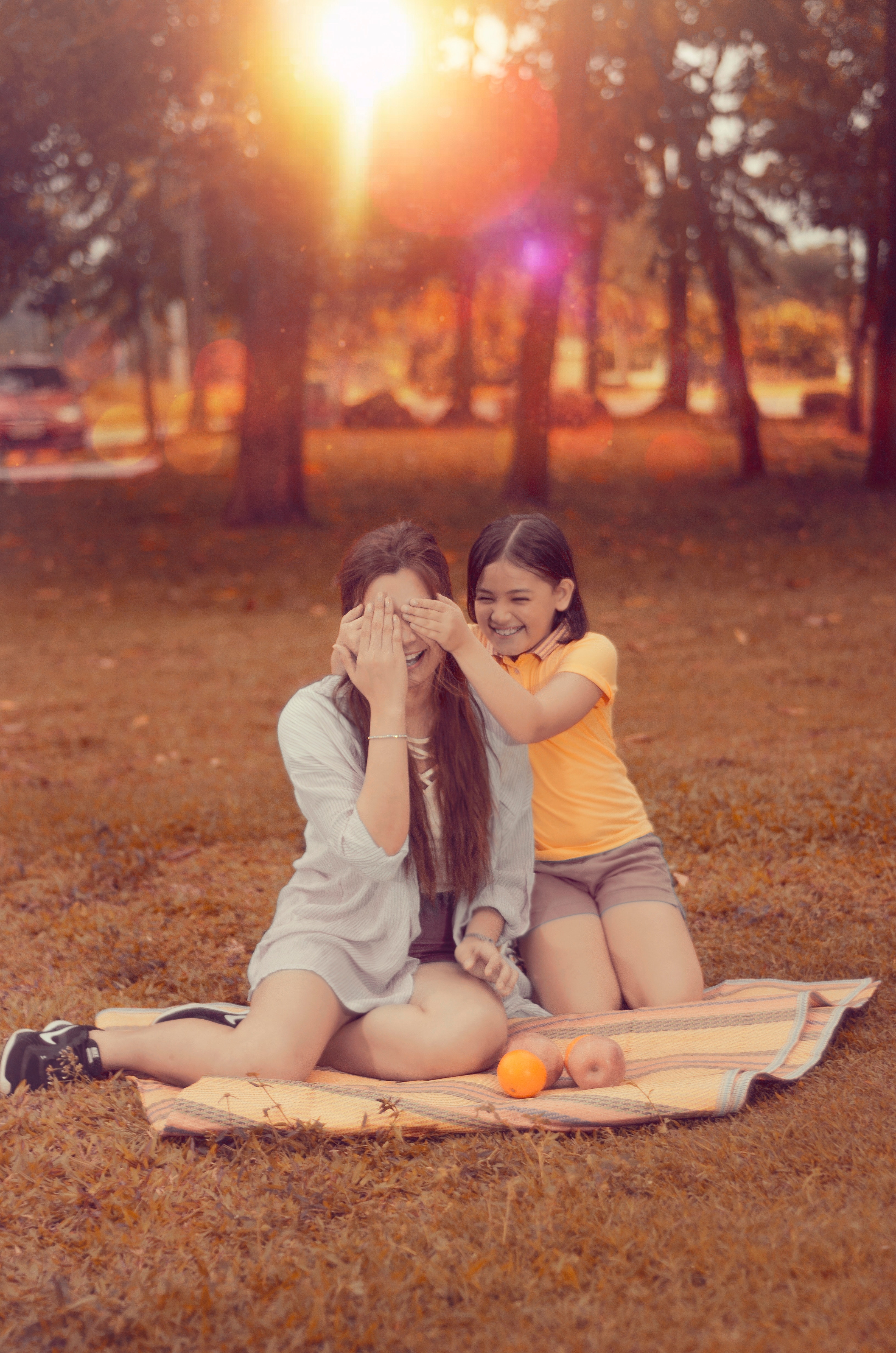 Two women sitting on brown picnic mat during sunset photo