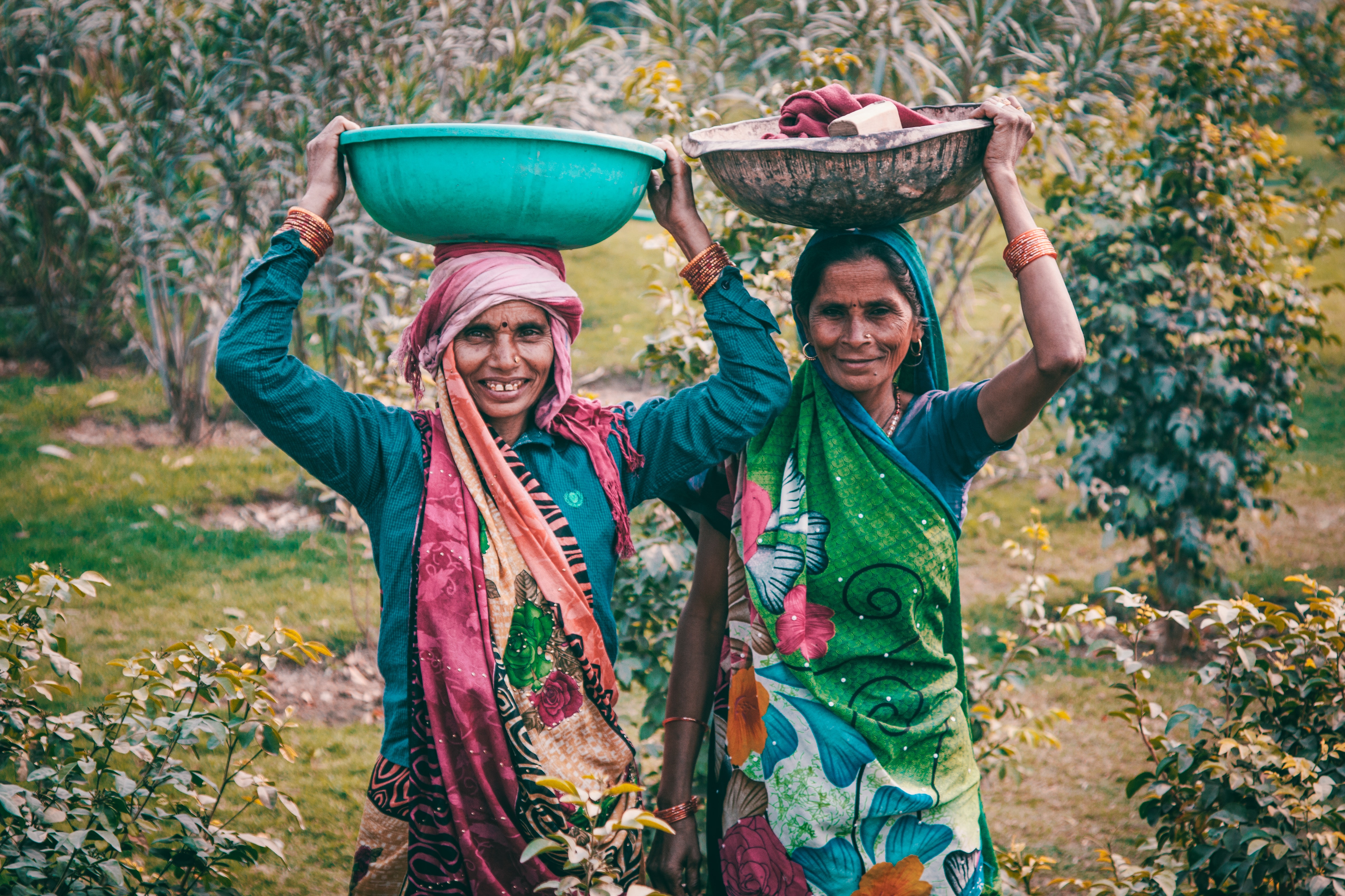 Two women wearing traditional dress carrying basins photo