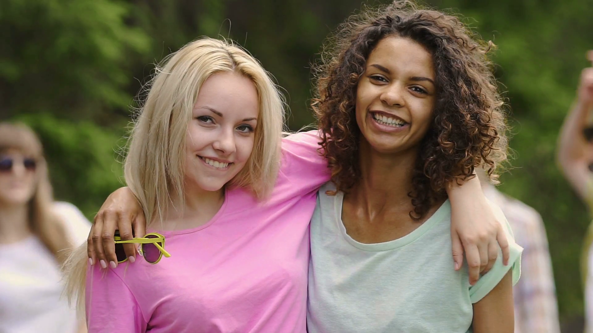 Two young beautiful multiracial women hugging and smiling to camera ...
