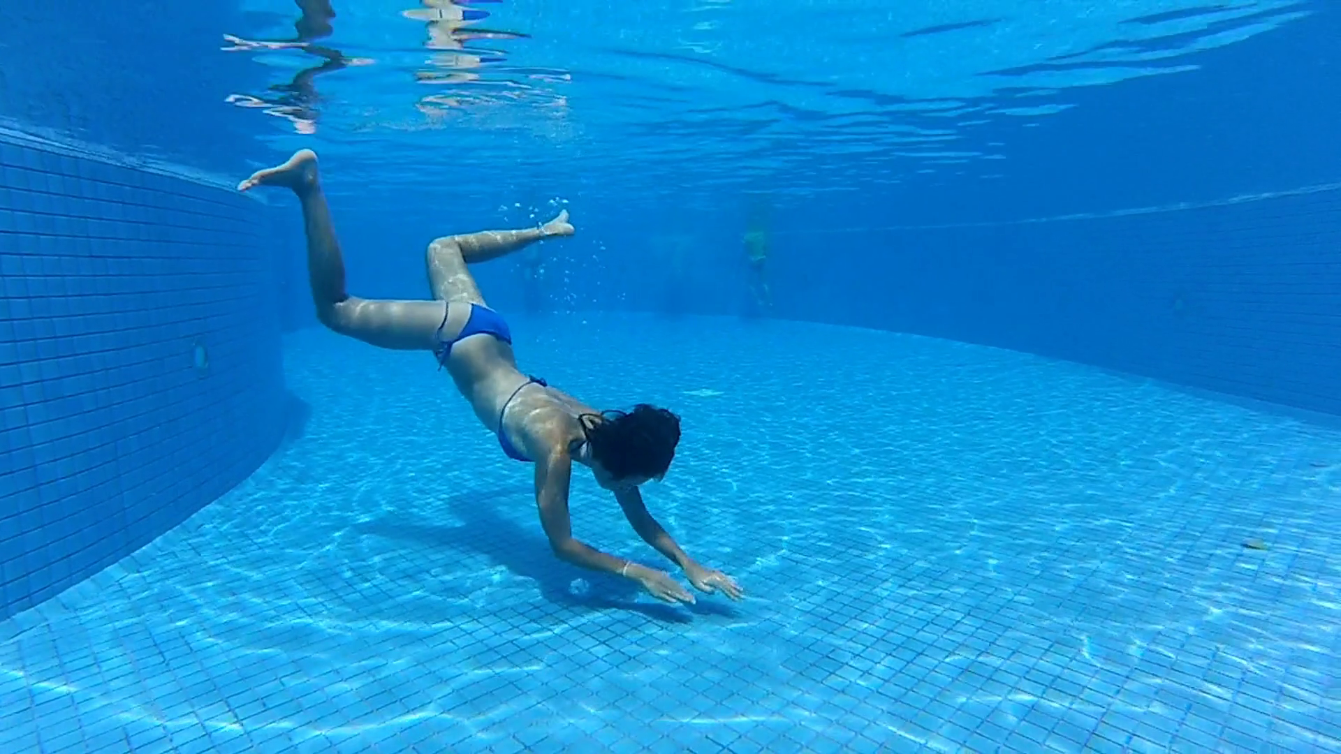 young girl swimming underwater in a blue pool under water gopro ...