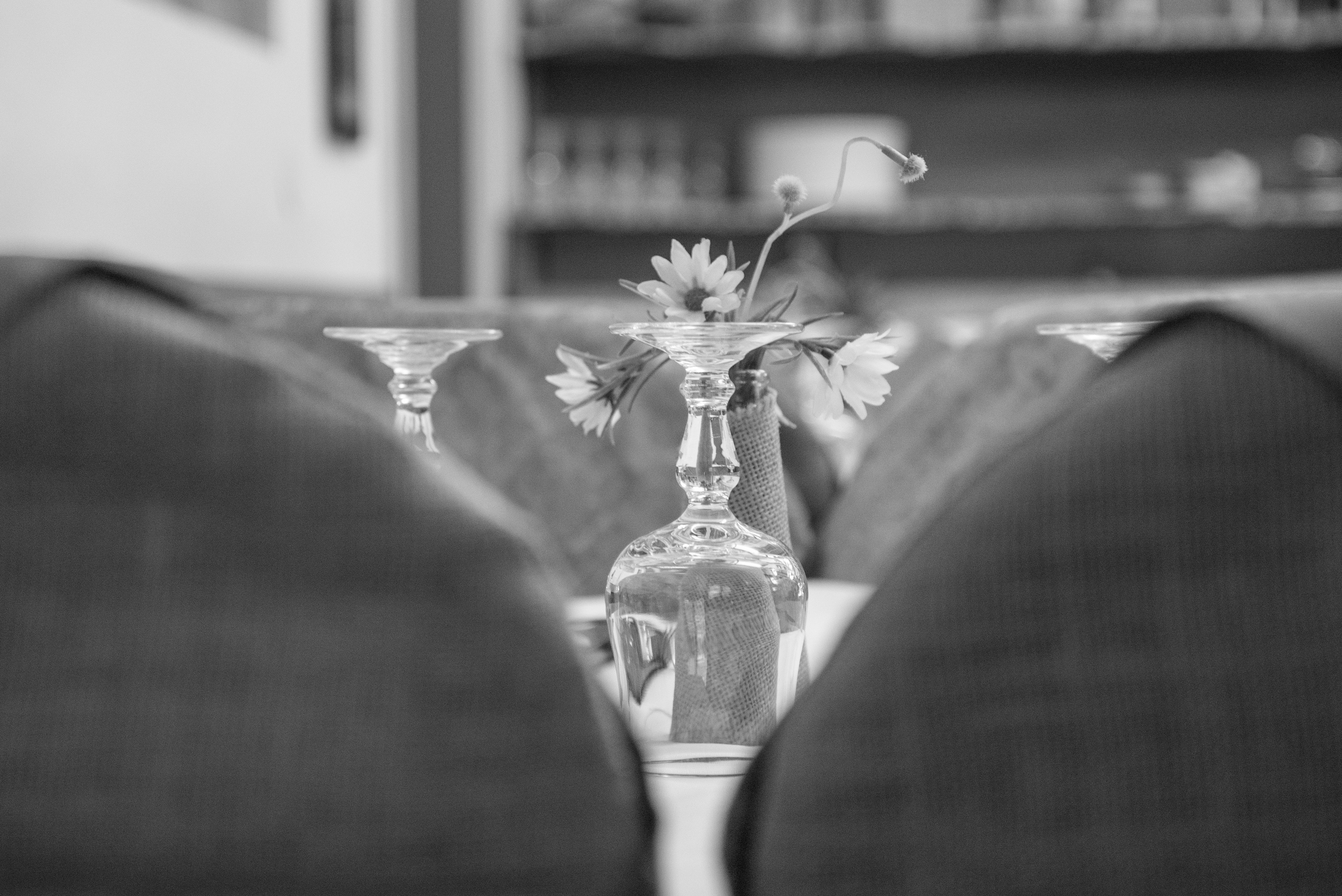 Upside down wine glass behind the flower grayscale photo
