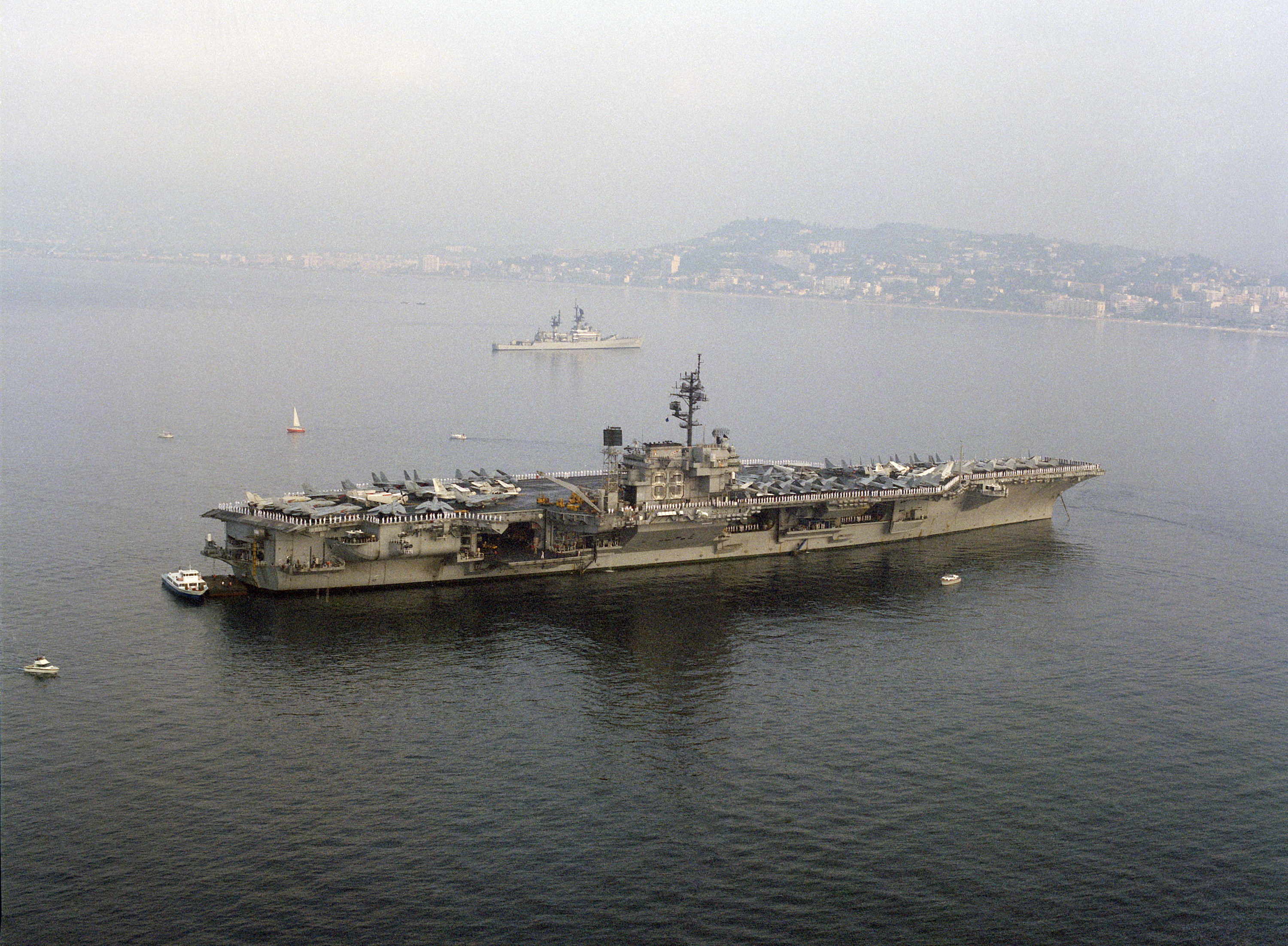 Uss kitty hawk (cv 63) anchored off the coast of cannes, france. the guided missile cruiser uss josephus daniels (cg 27) is in the background. photo