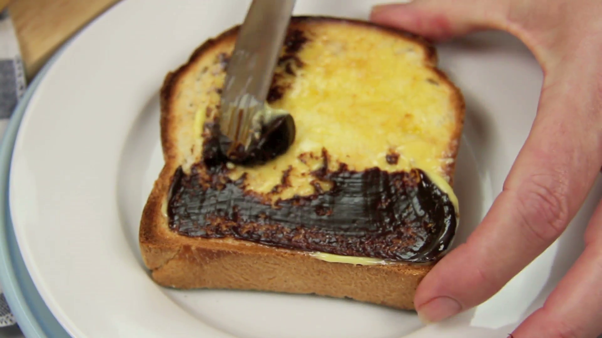 Vegemite being spread on to melted butter on a hot toast slice ...