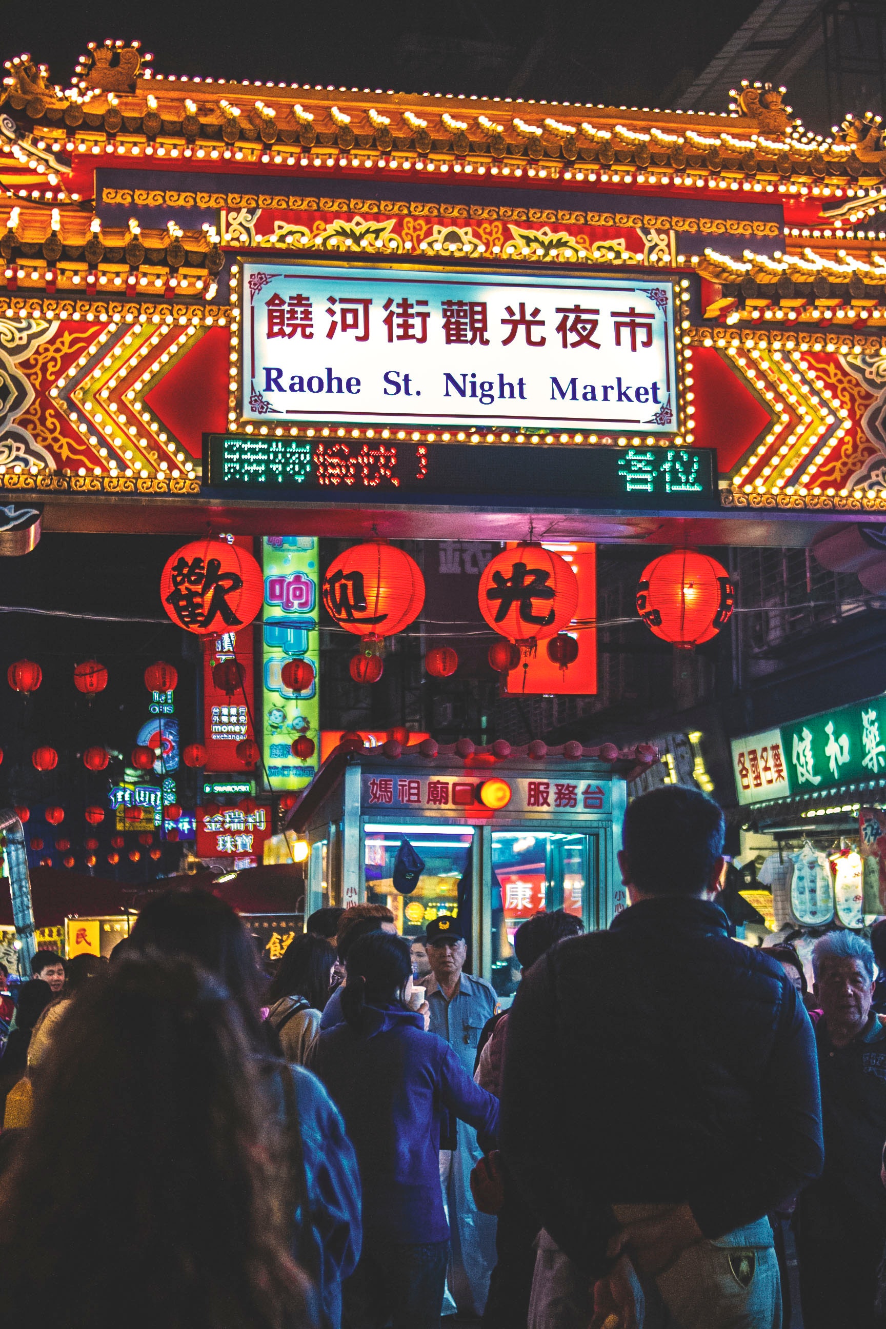 View of raohe st. night market arch with kanji texts and group of people photo