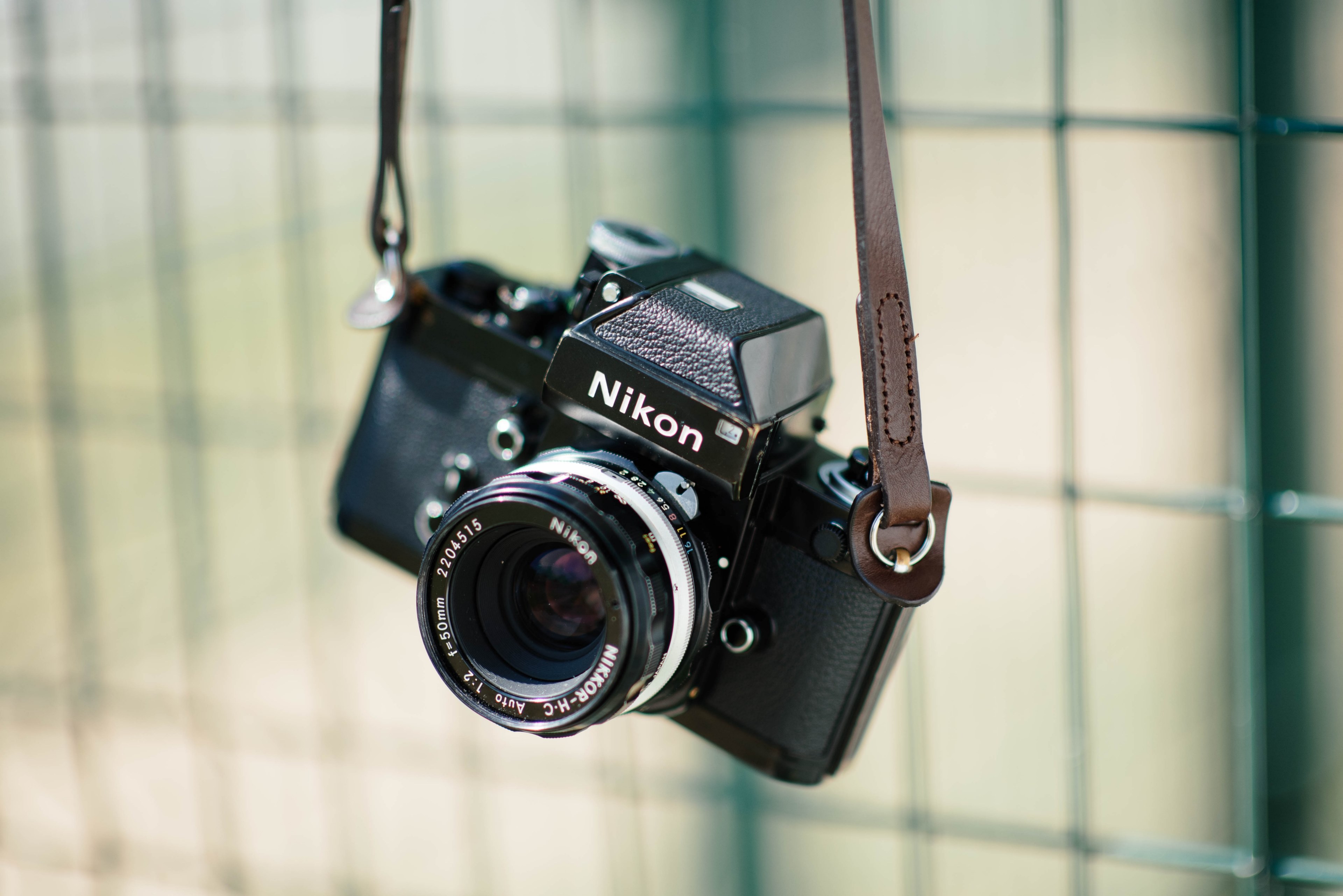 nikon vintage camera with a leather strap hanging from a metal ...