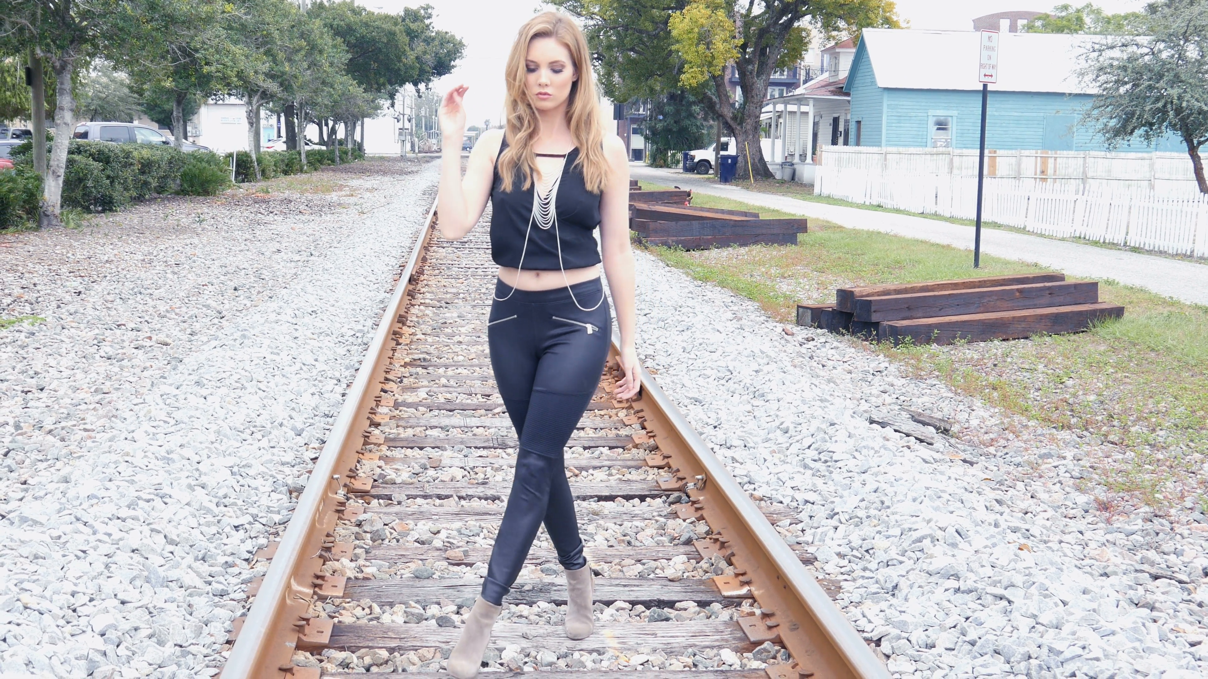 Hipster rock and roll girl walking towards camera on rail road ...