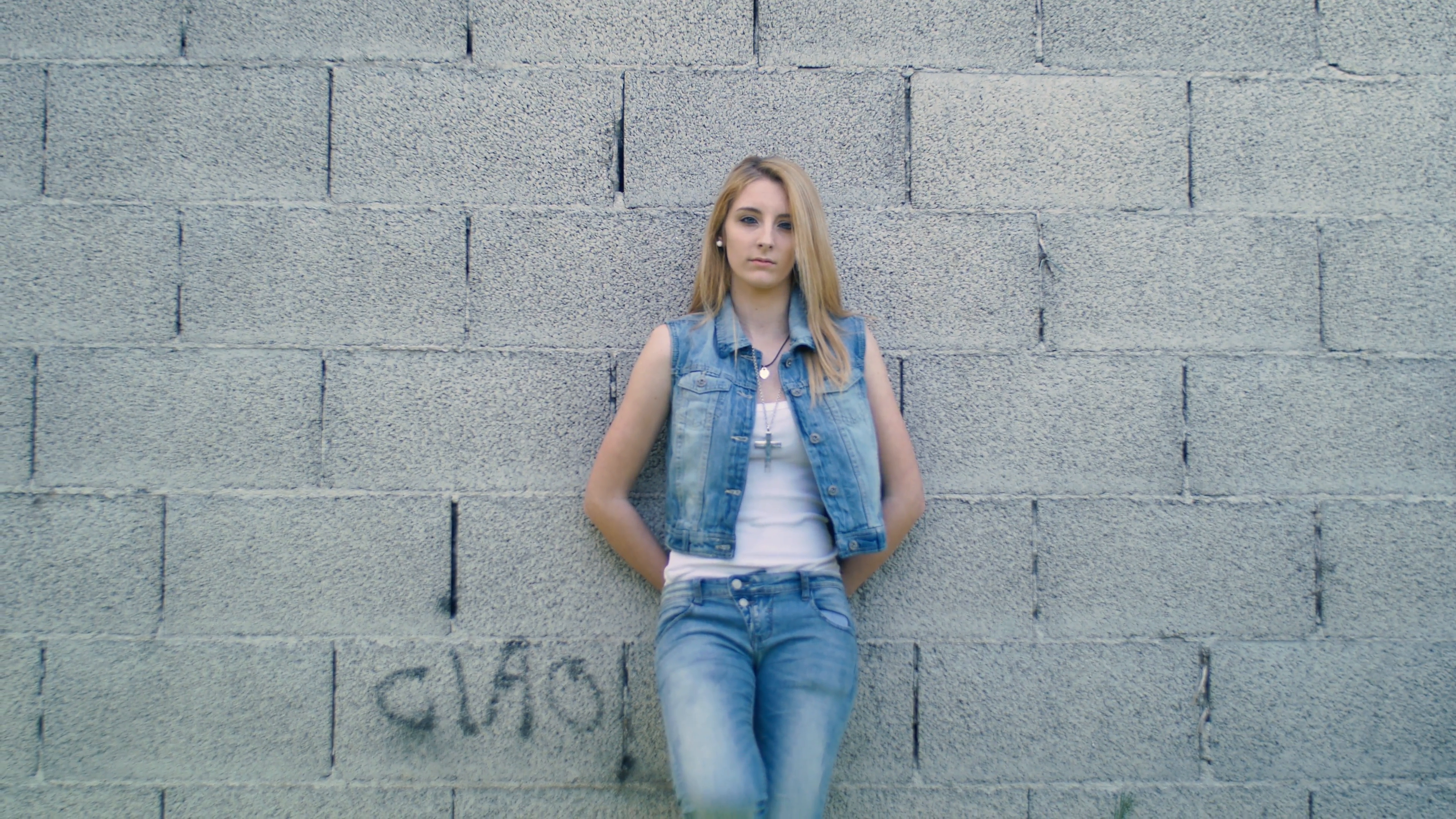 Handheld shot of blonde girl leaning on the wall. Shot in 4K Stock ...