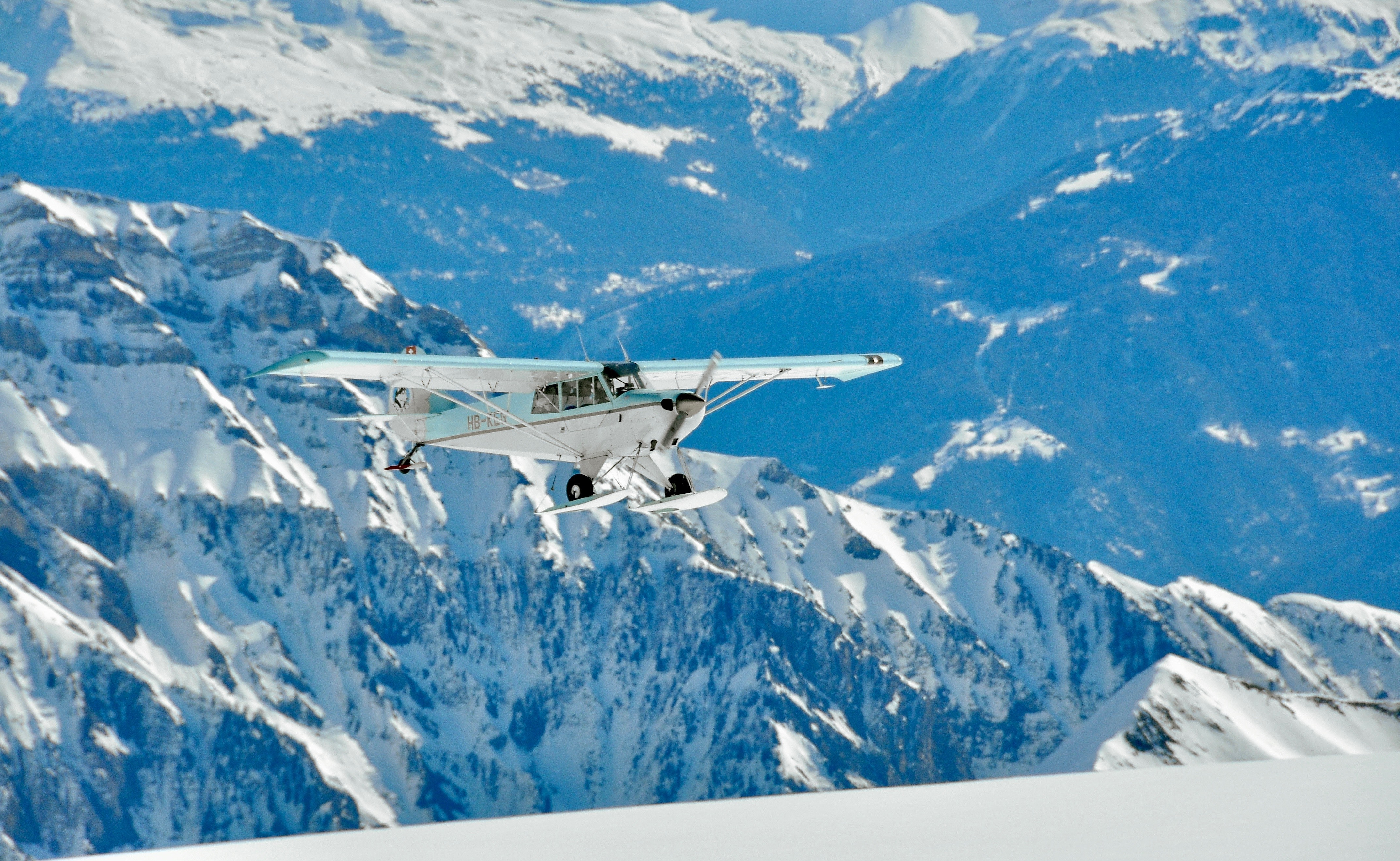 White and green monoplane flying above mountains photo