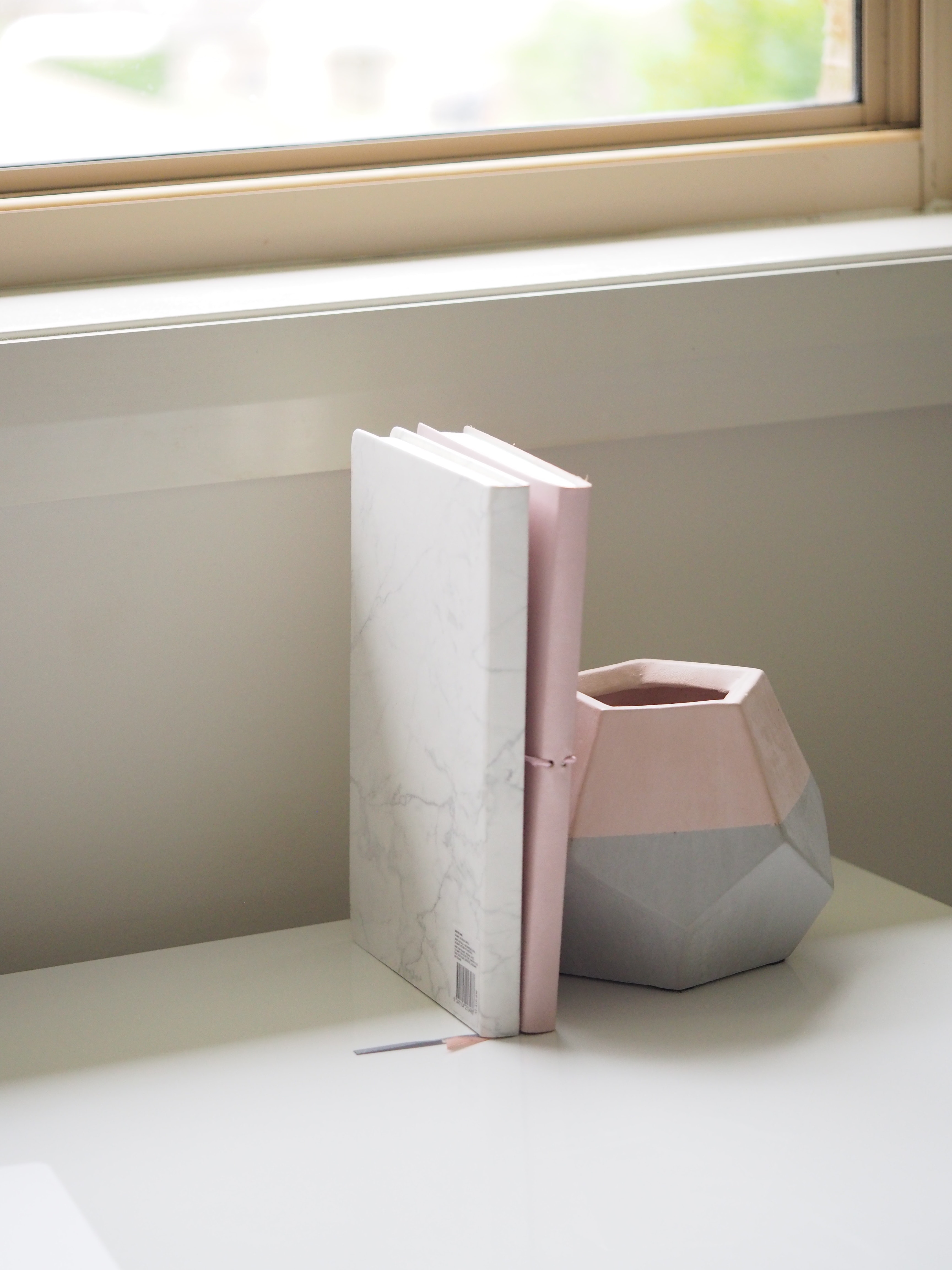 White and pink books piled beside pink and gray ceramic vase photo