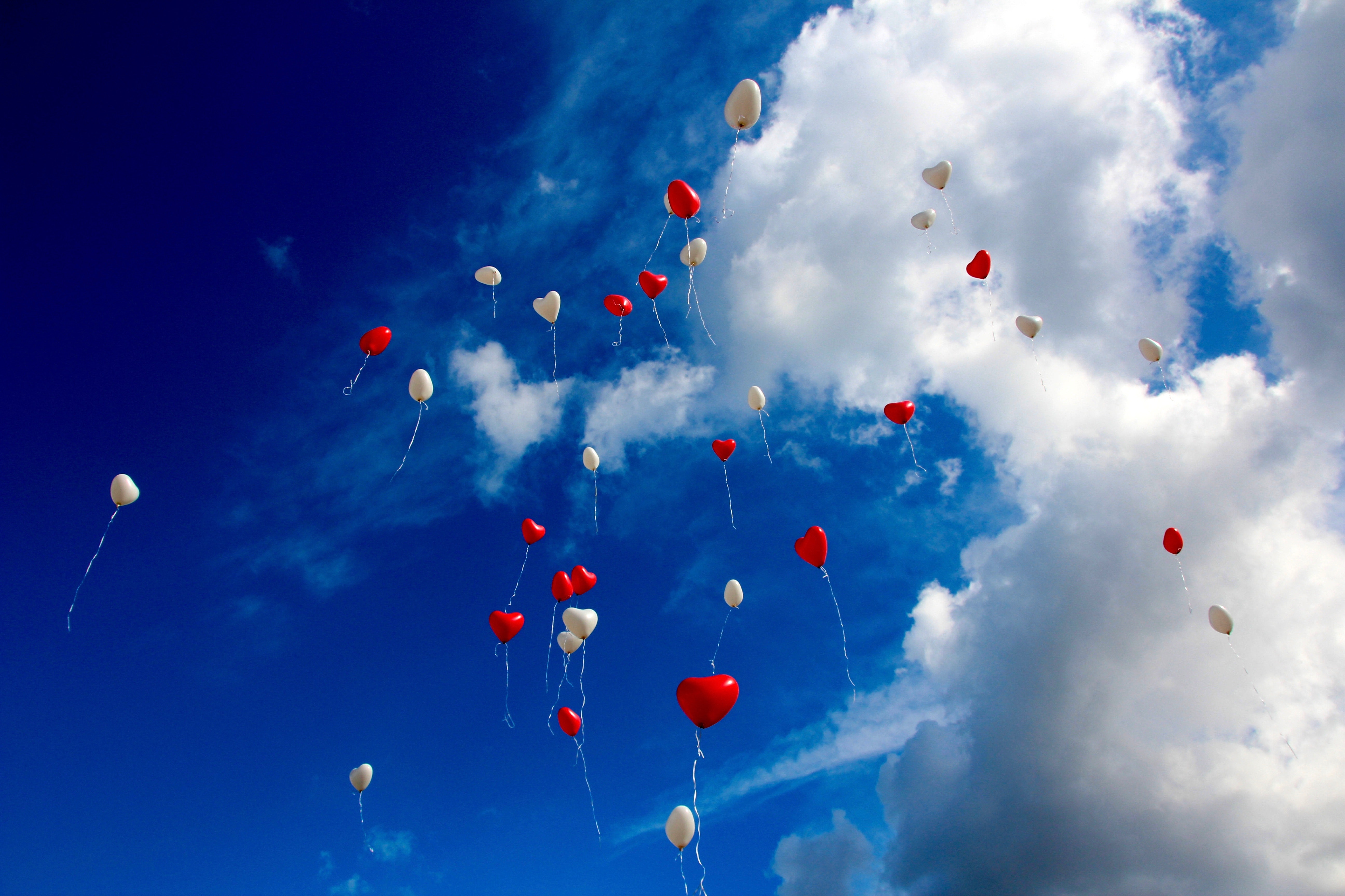 White and red plastic heart balloon on sky during daytime photo
