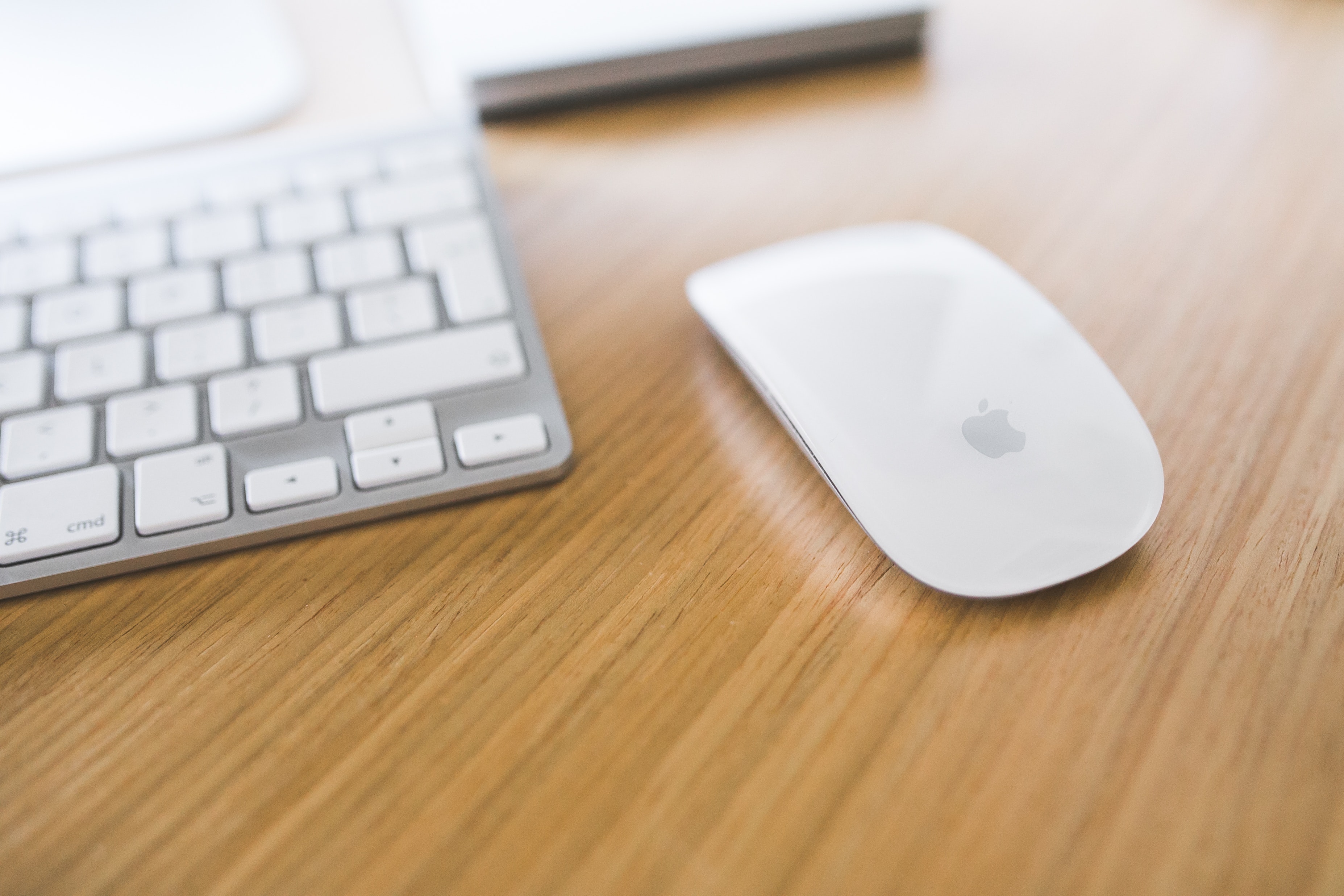 White apple mouse and keyboard on a wooden desk photo