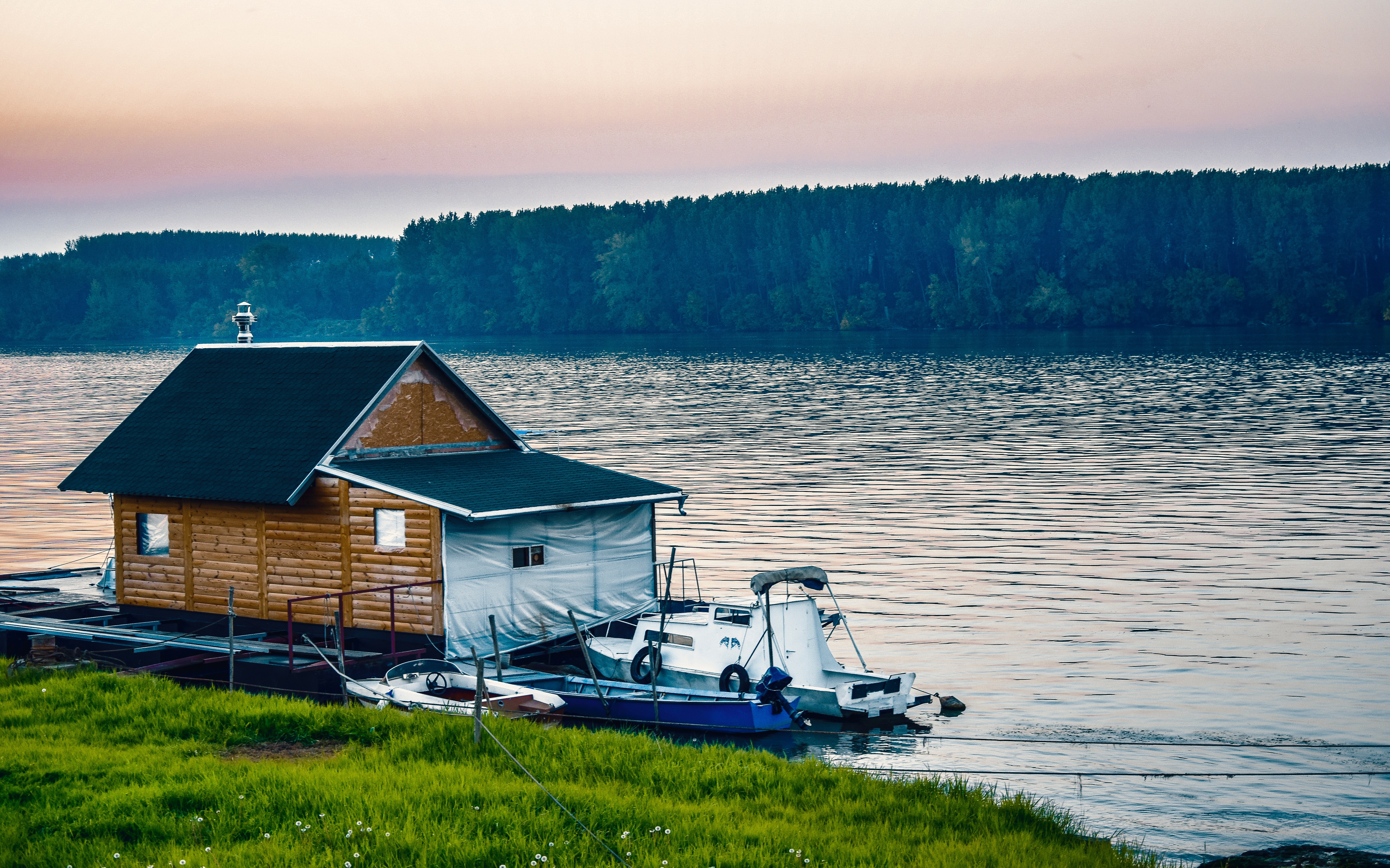 White boat beside wooden house on water near forest photo