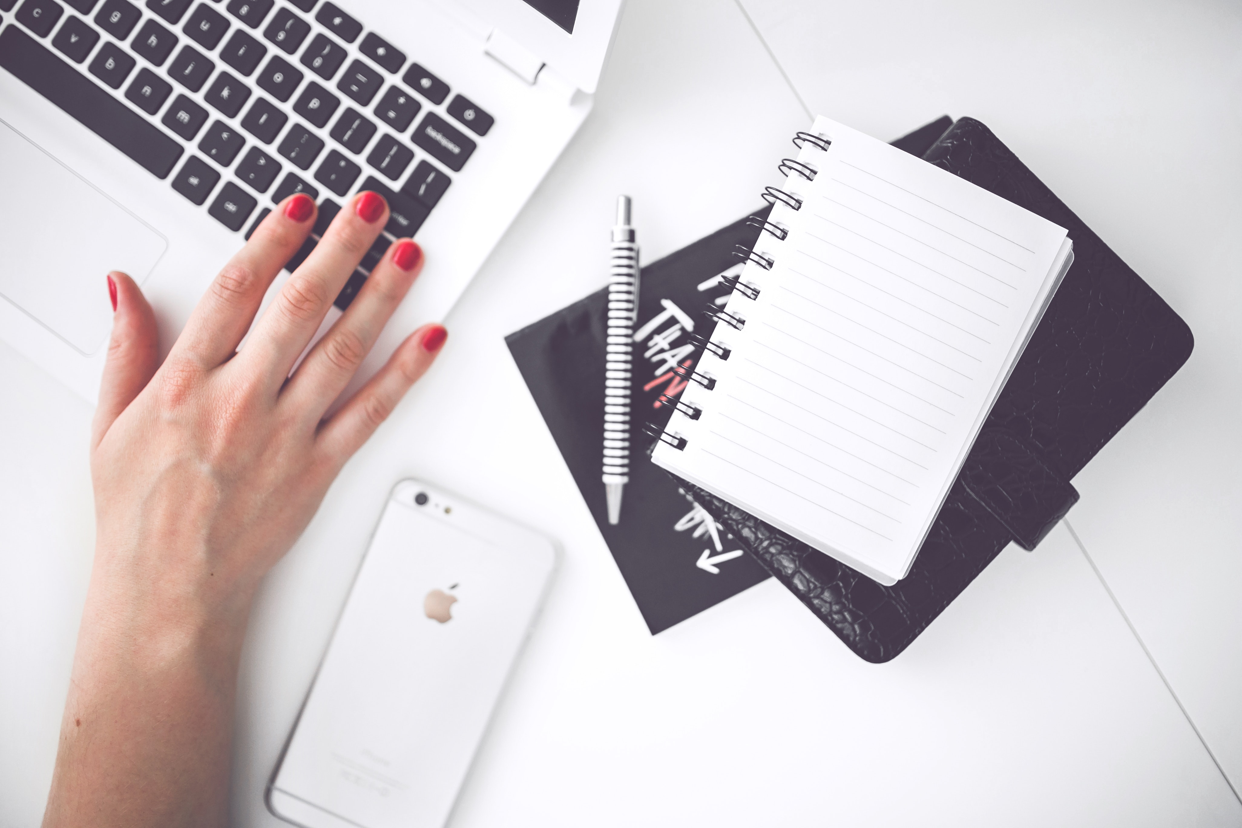 White laptop, female hand, note, pen, phone, desk photo
