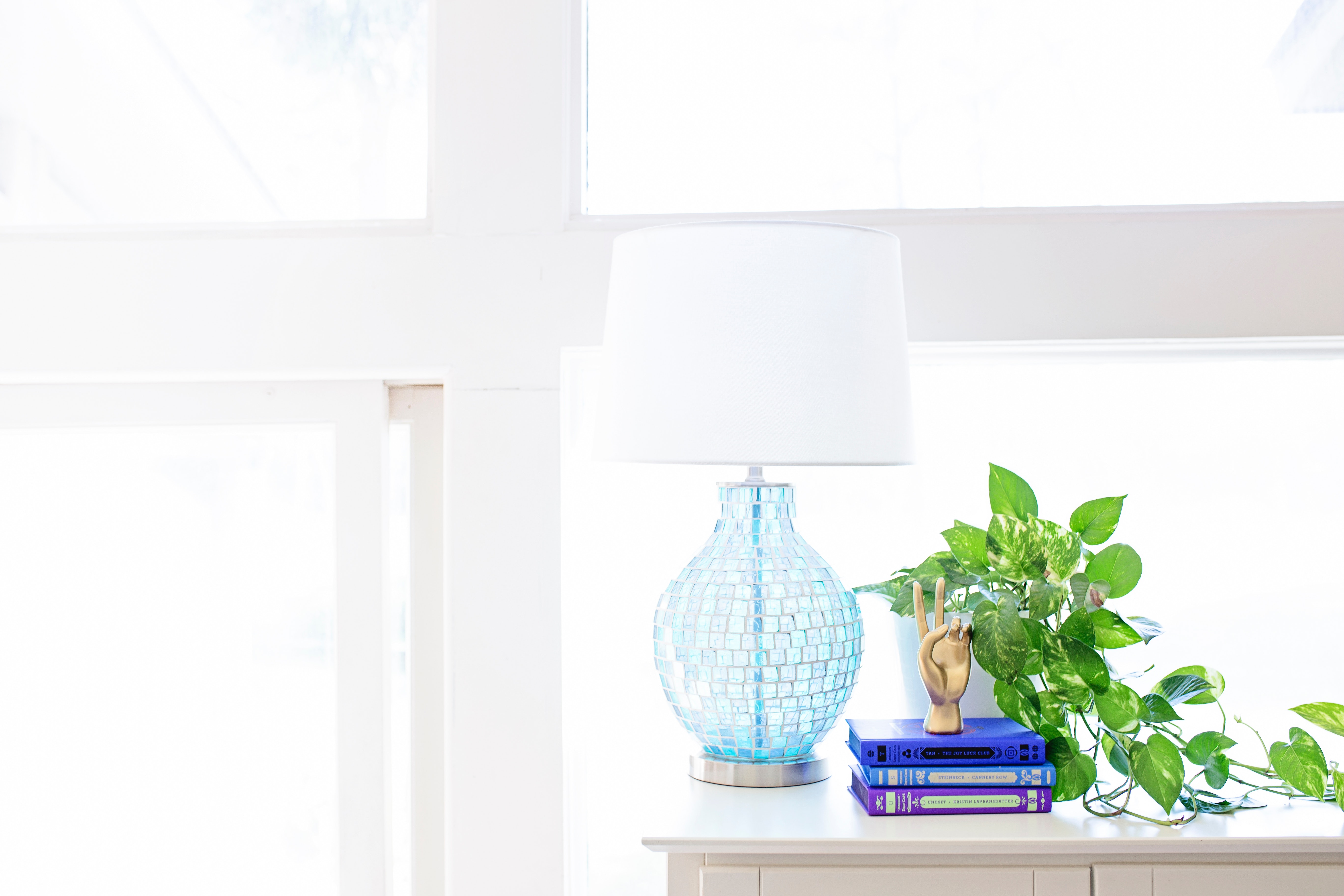 White table lamp on sideboard near plant and books photo