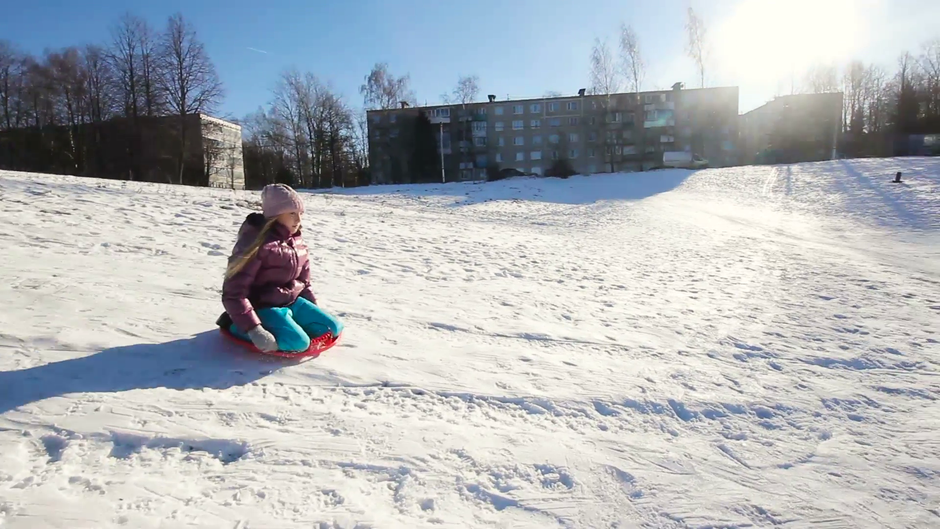 Girl sledging down hill, bright and joyful winter scene. Happy girl ...