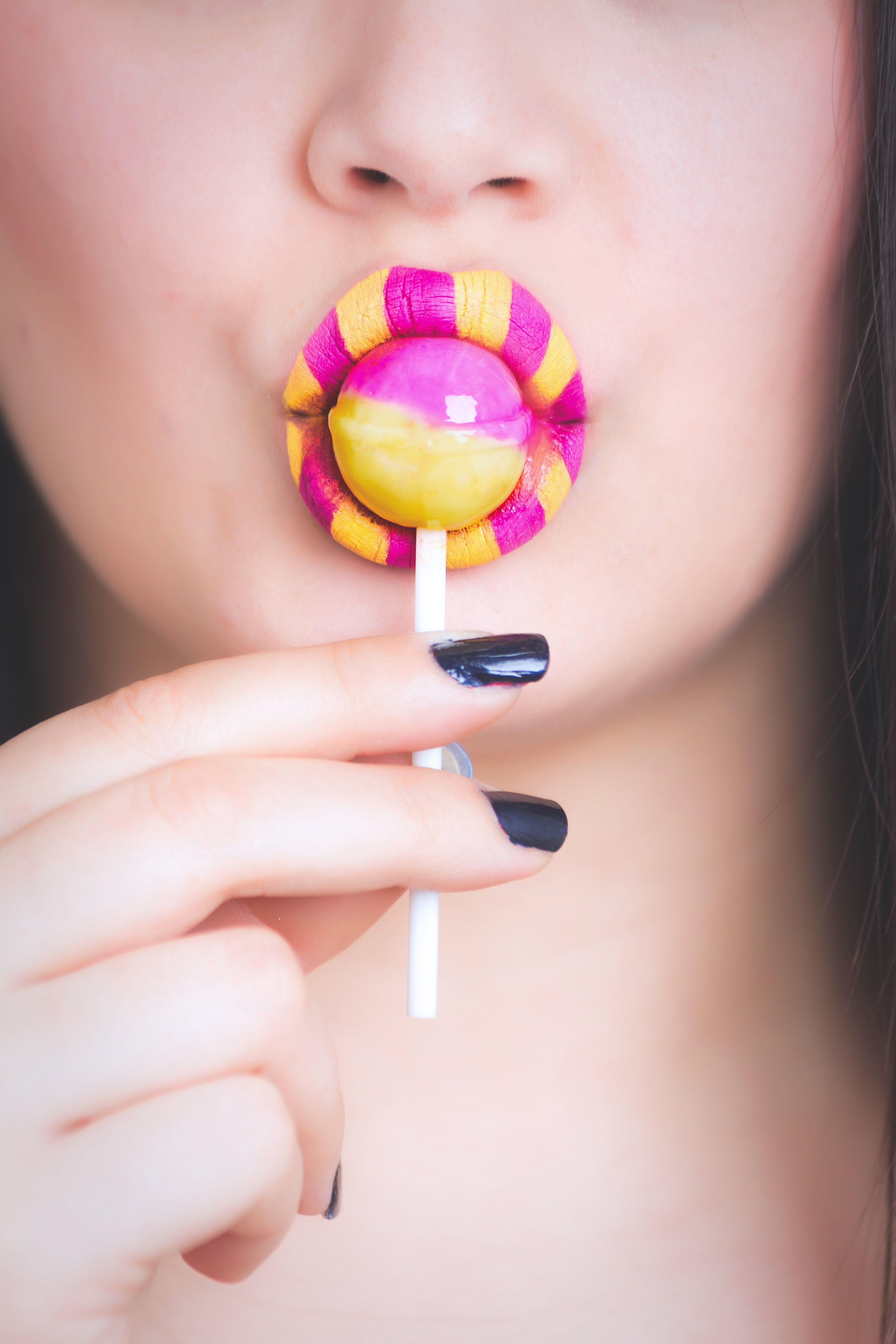 Woman eating pink and yellow lollipop photo