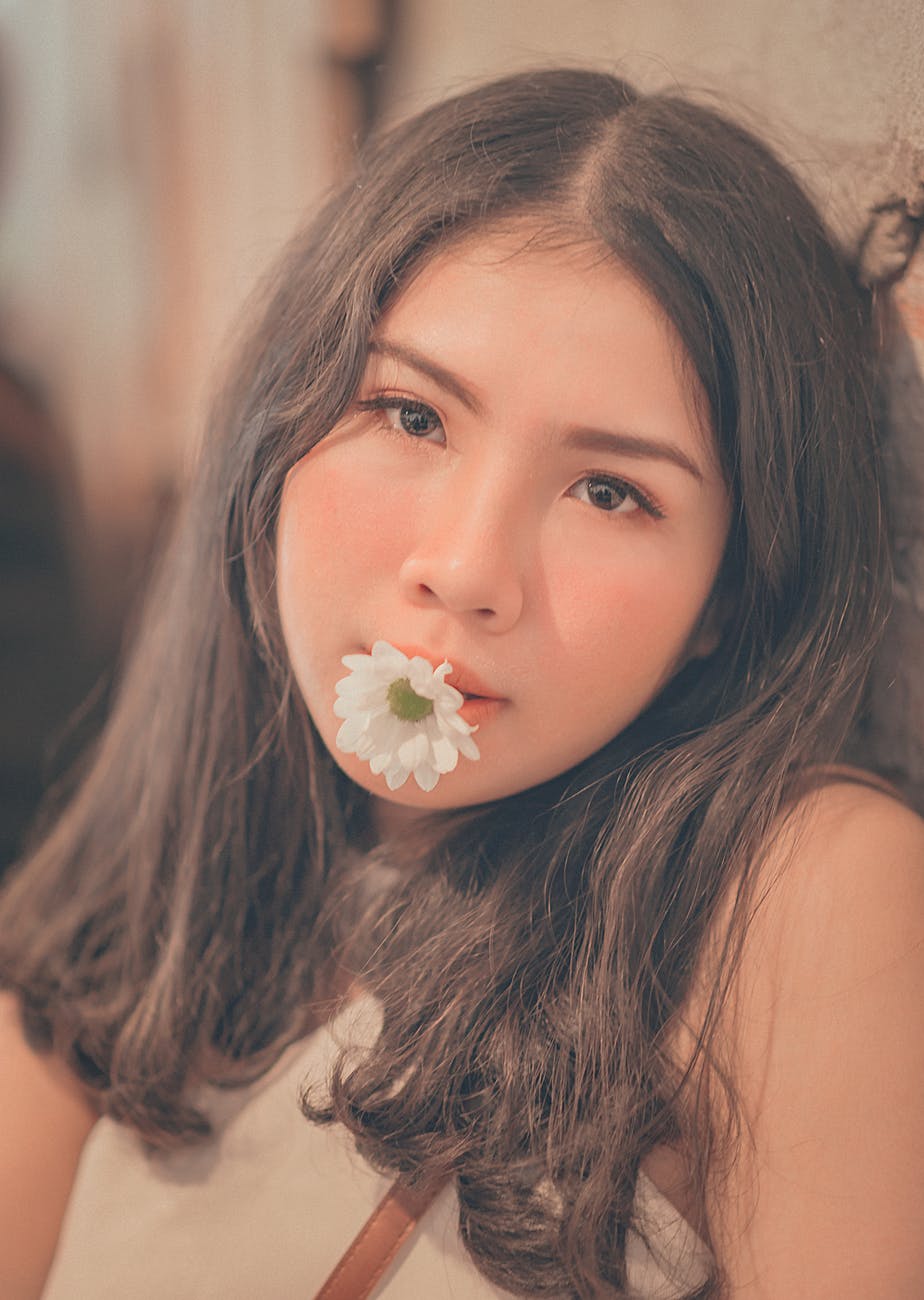 Woman having a white daisy on her mouth photo