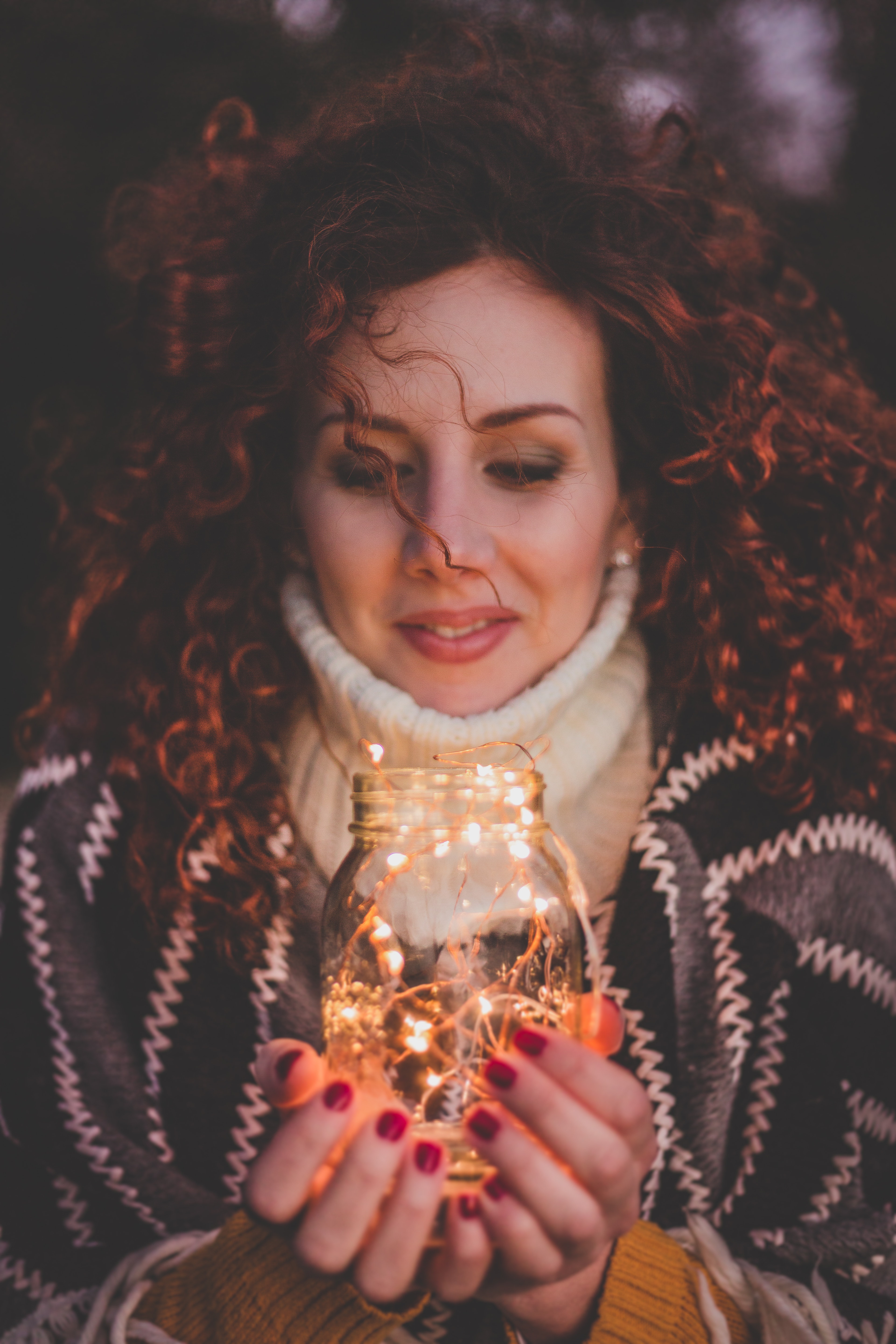 Woman holding mason jar with string lights inside photo