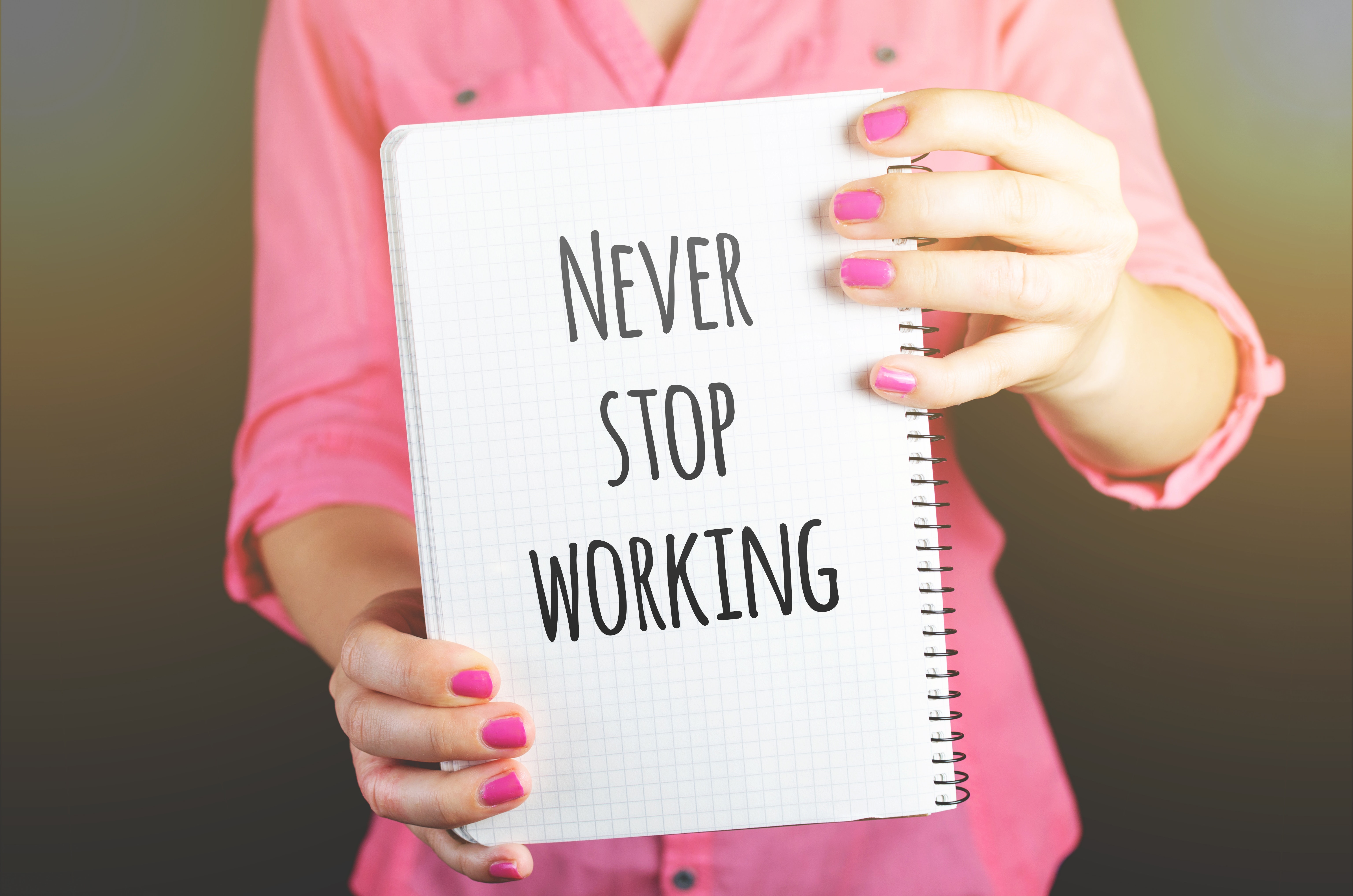 Woman holding never stop working print notebook photo