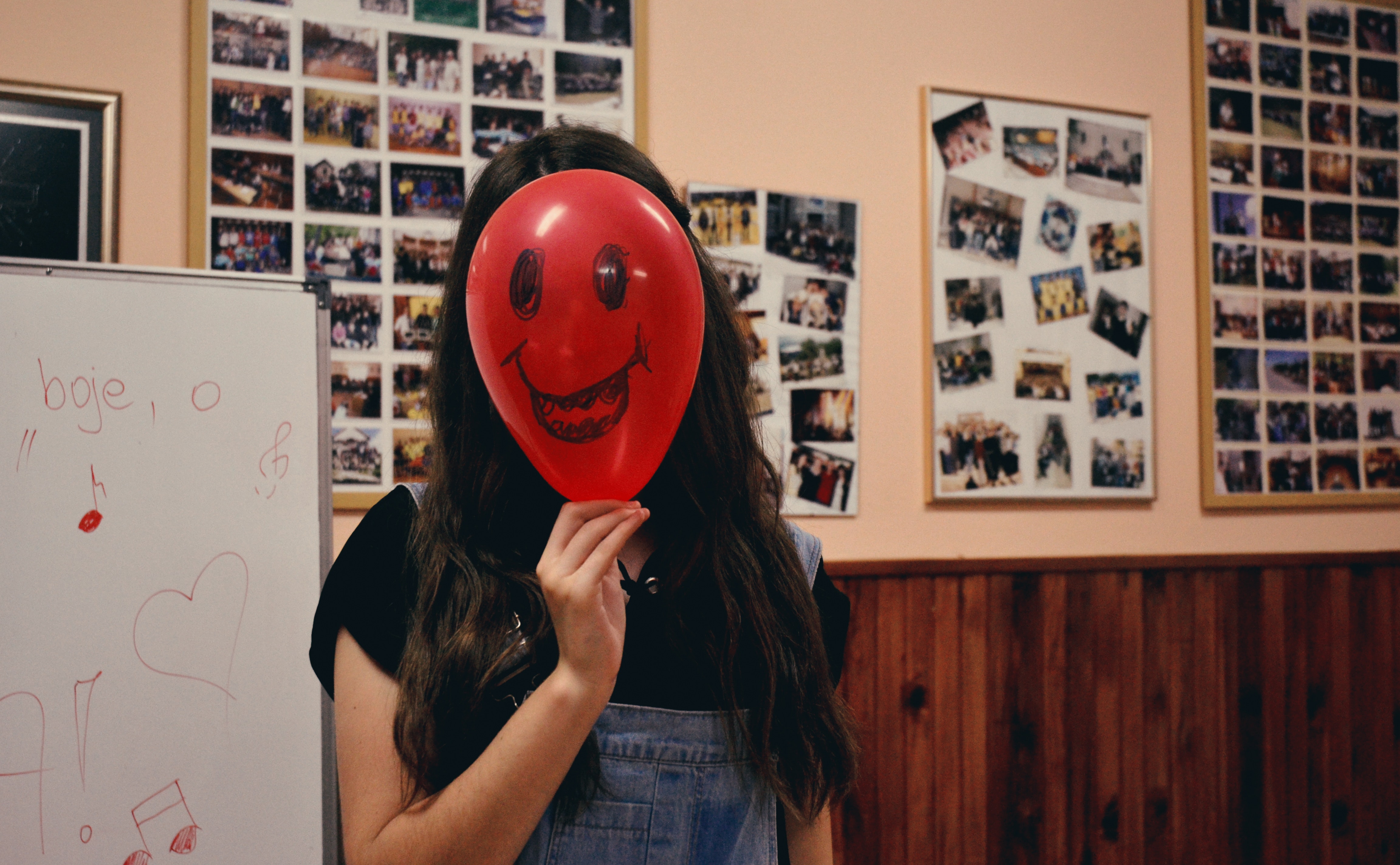 Woman holding red balloon on her face photo inside classroom