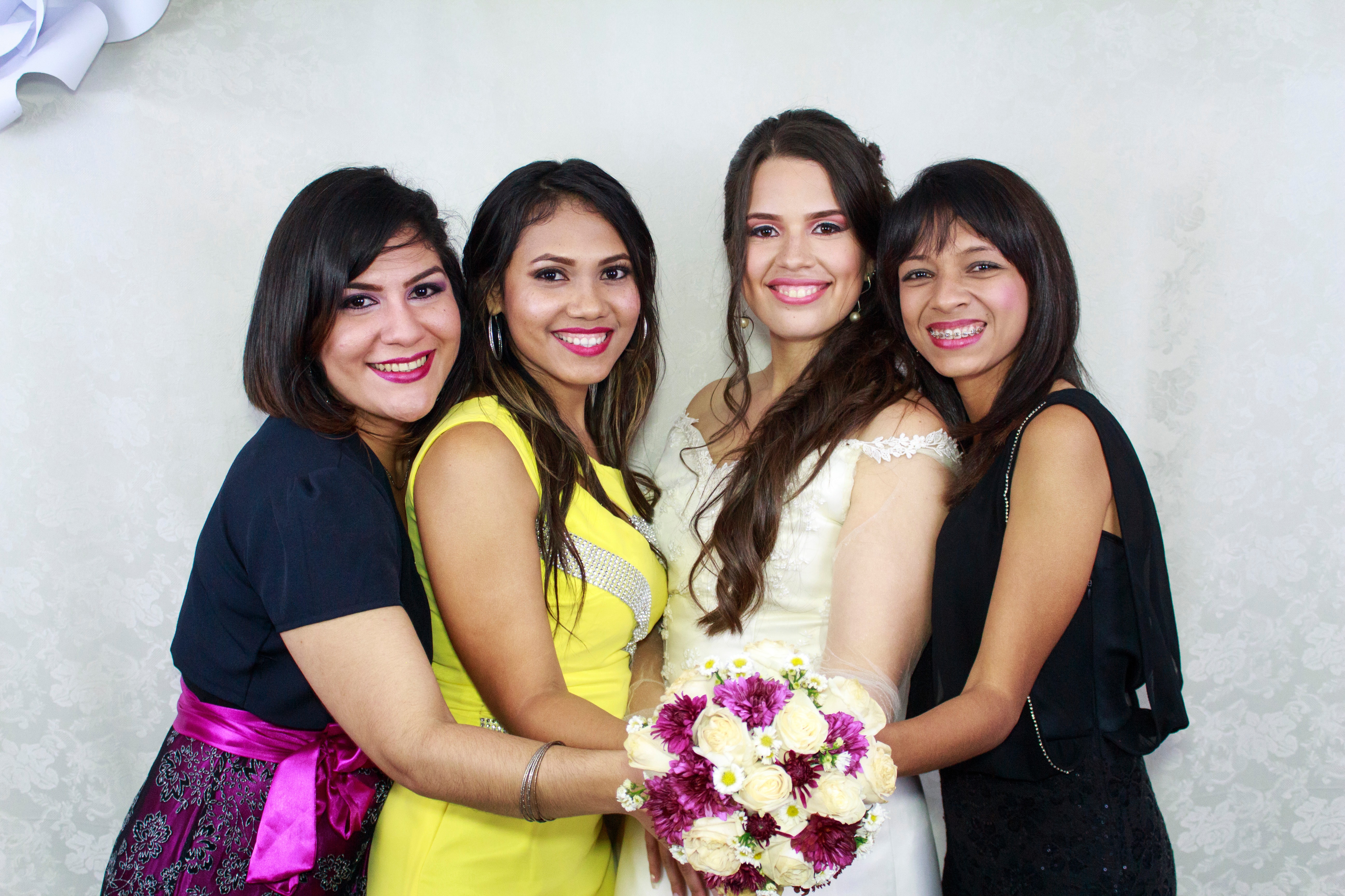 Woman in beige wedding dress holding bouquet flower together with other three woman in assorted colors of dresses photo