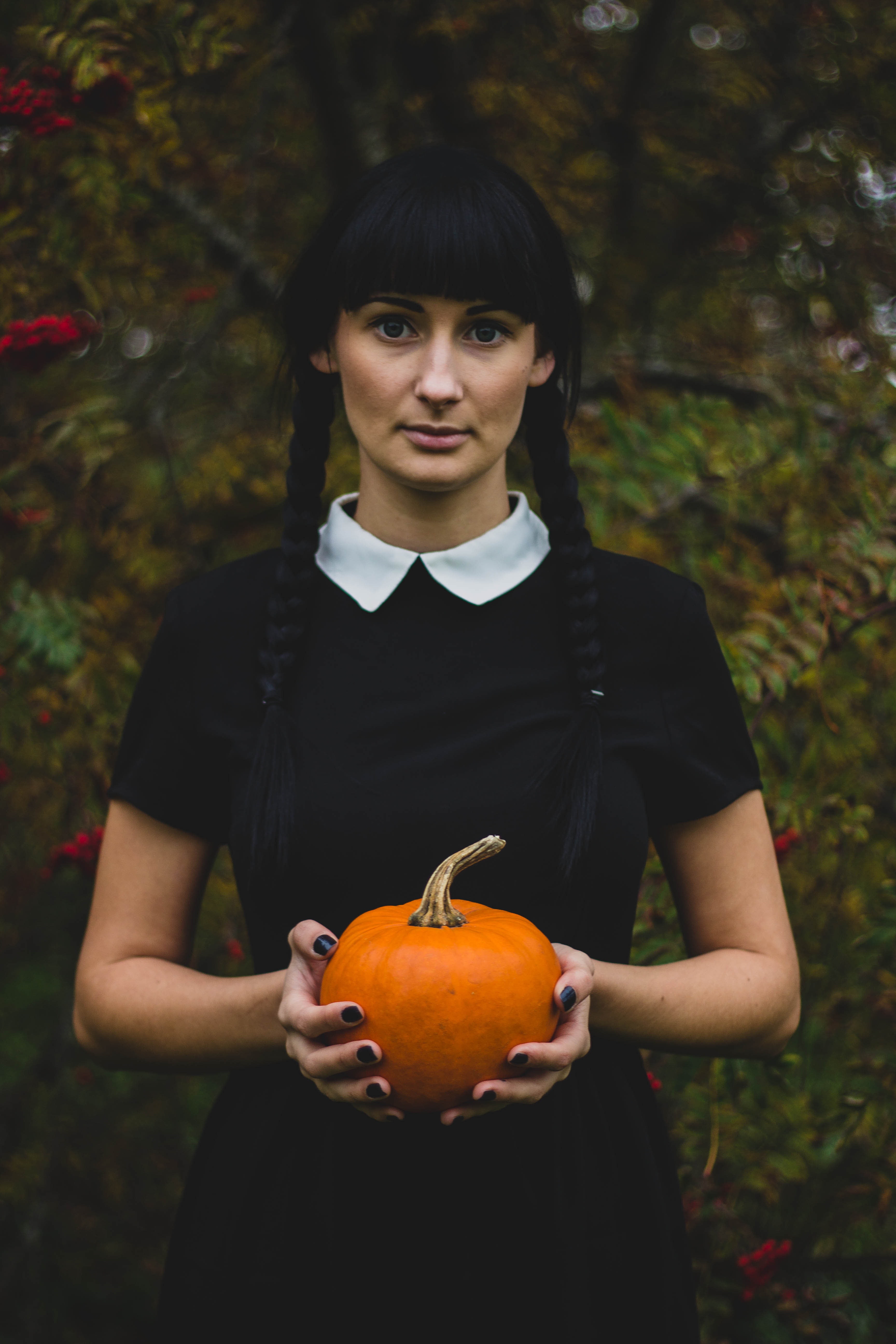 Woman in black and white collared dress holding pumpkin during daytime photo