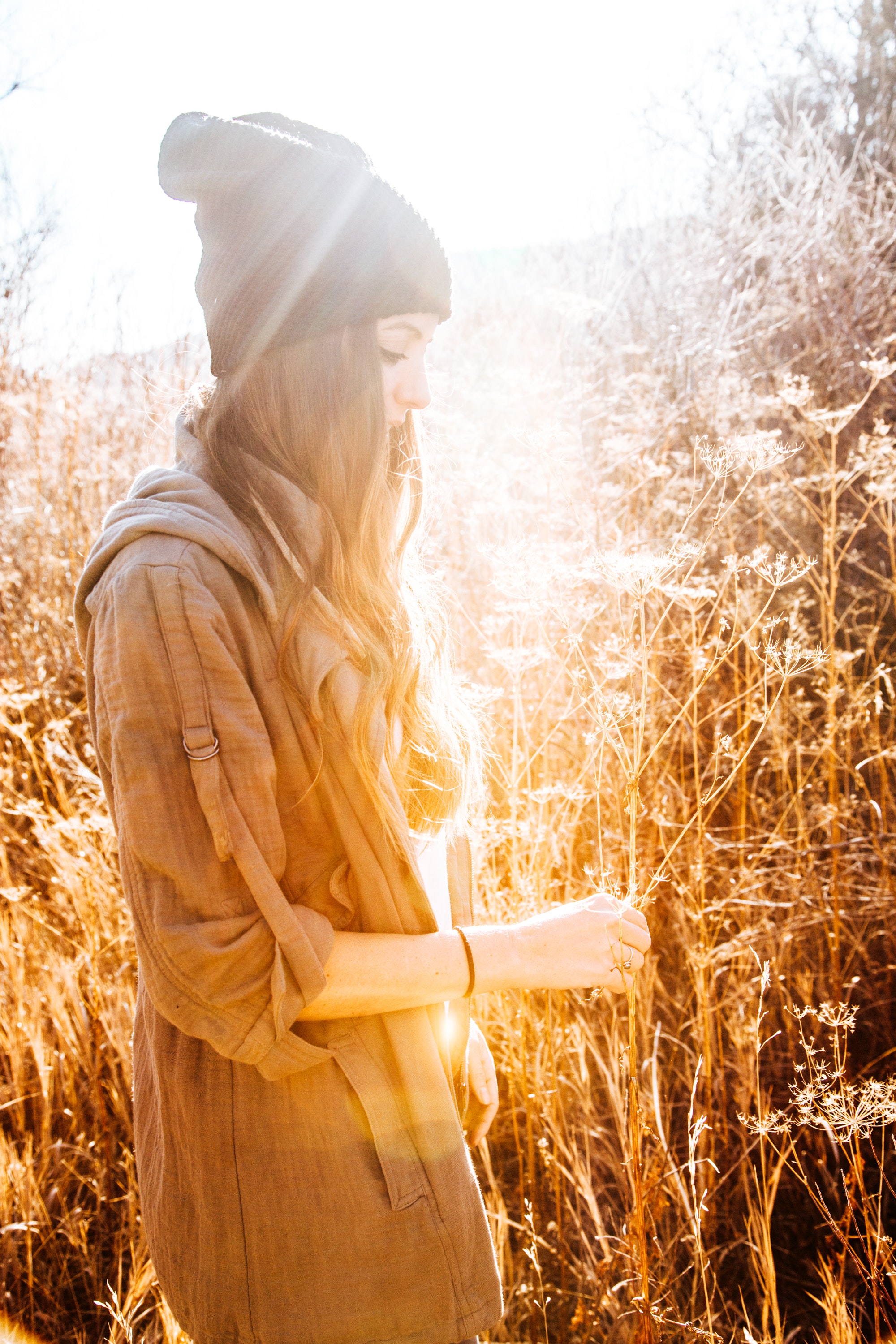 Woman in black beanie standing next to tall grass photo